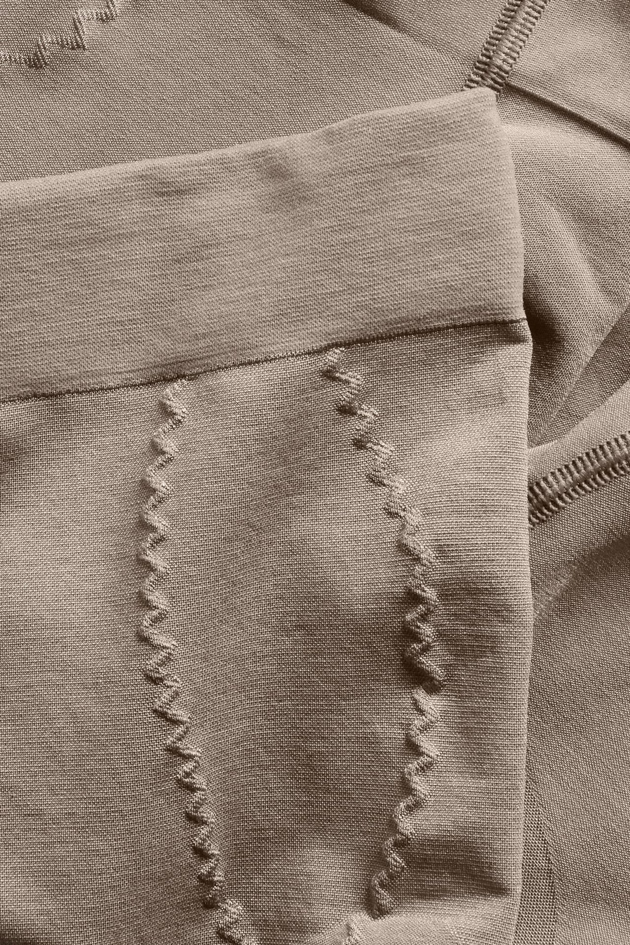 Nærbilde av sømløse brune shapingshorts med høy støtte og teksturerte bølgemønstre.