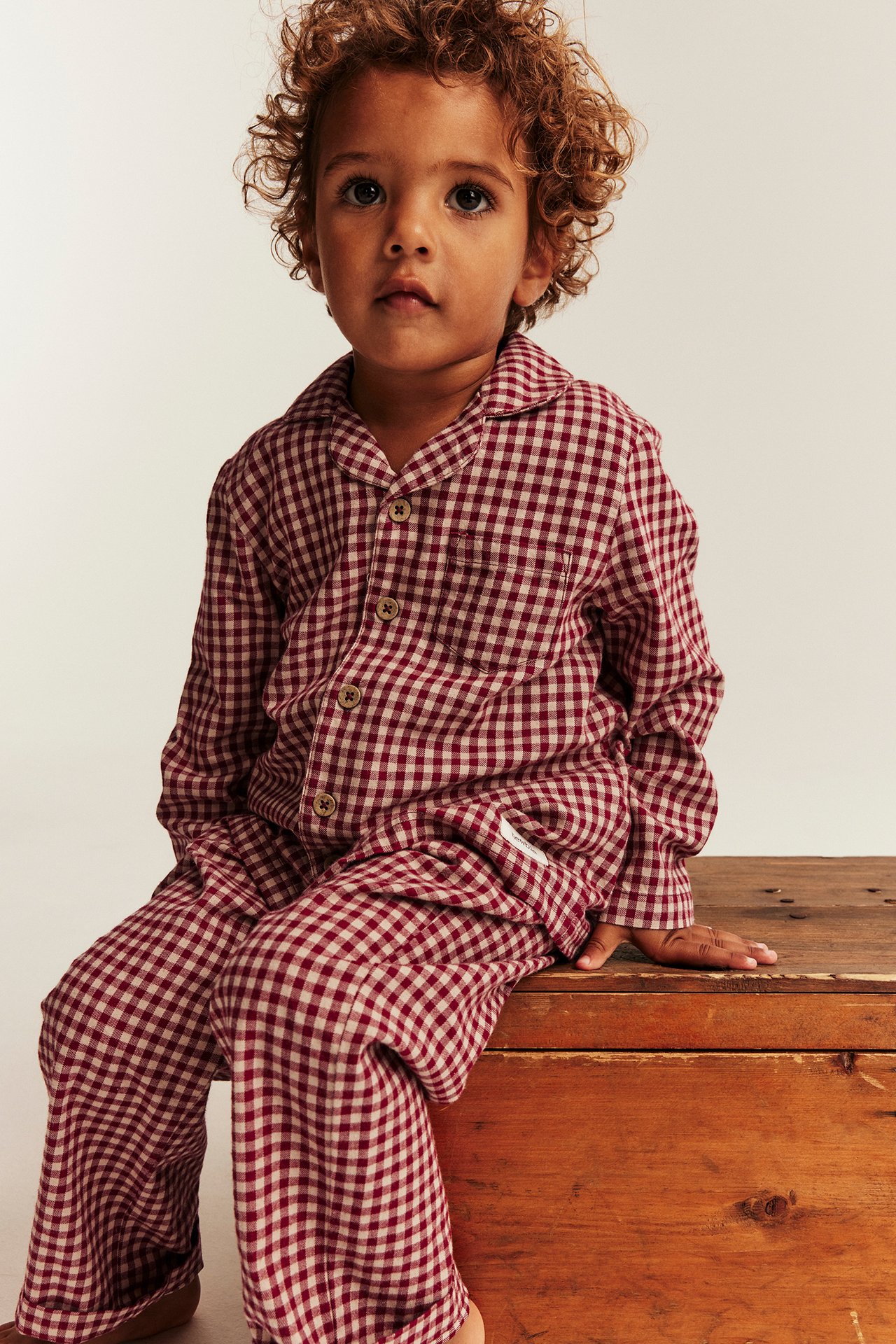 Edestä kuvattu lapsi yllään punaiset ja beiget ruudulliset pyjamat.