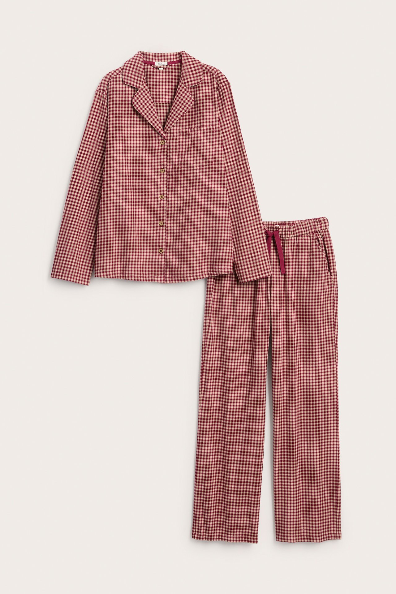 Edestä näkymä punabeigestä ruudullisesta pyjamasta, jossa on pitkähihainen paita ja housut.