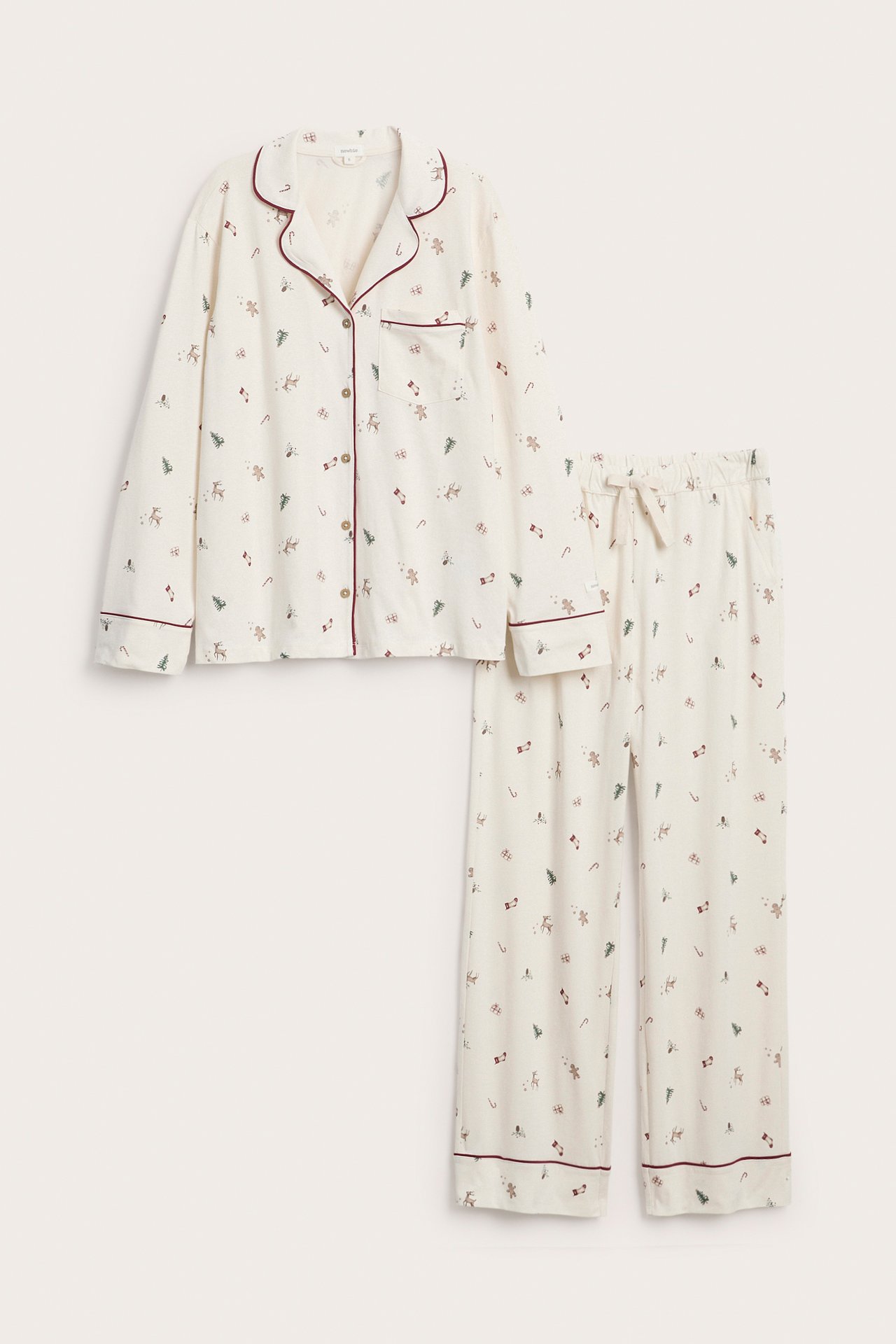 Frontal visning av kremfarget langermet pyjamassett for kvinner med rød piping og julemønster.