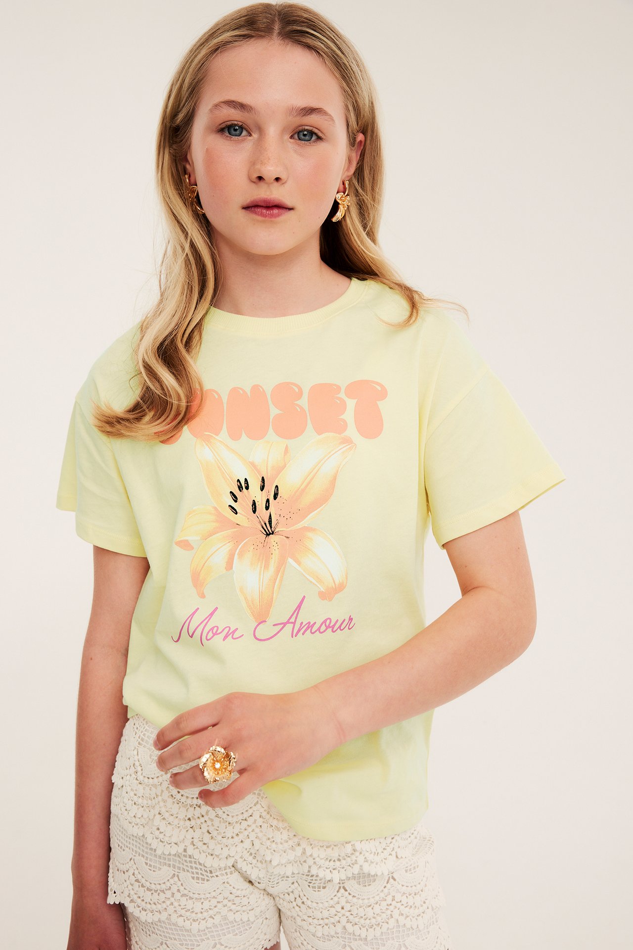 Ljusgul T-shirt med blomma och textmotiv fram, kvinnlig modell, kort ärm.