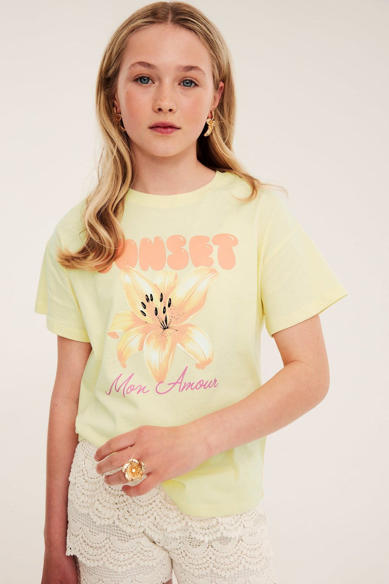 Ljusgul T-shirt med blomma och textmotiv fram, kvinnlig modell, kort ärm.