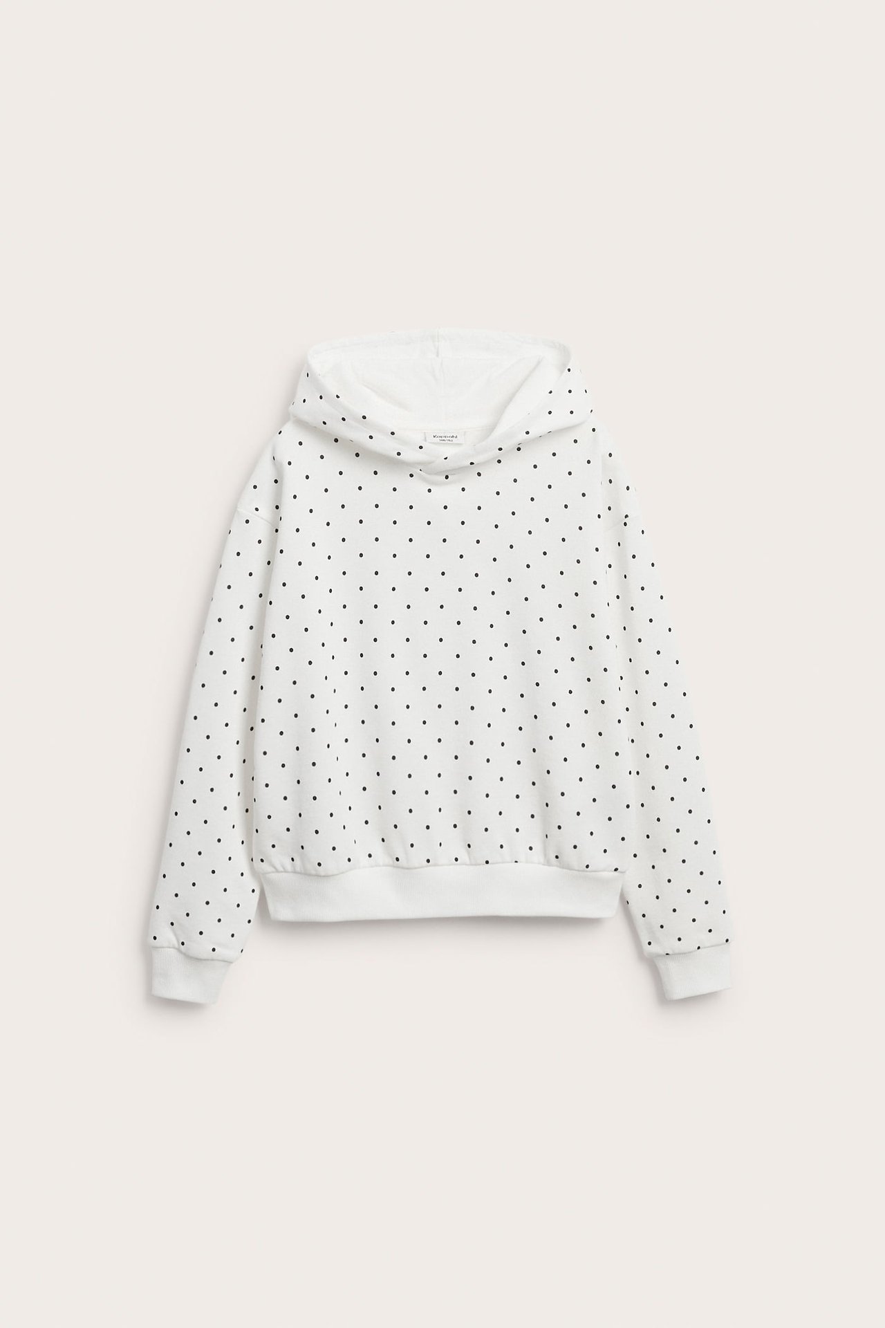 Widok z przodu białej bluzy z kapturem z mieszanki bawełny w czarne kropki, z kapturem i ściągaczami.