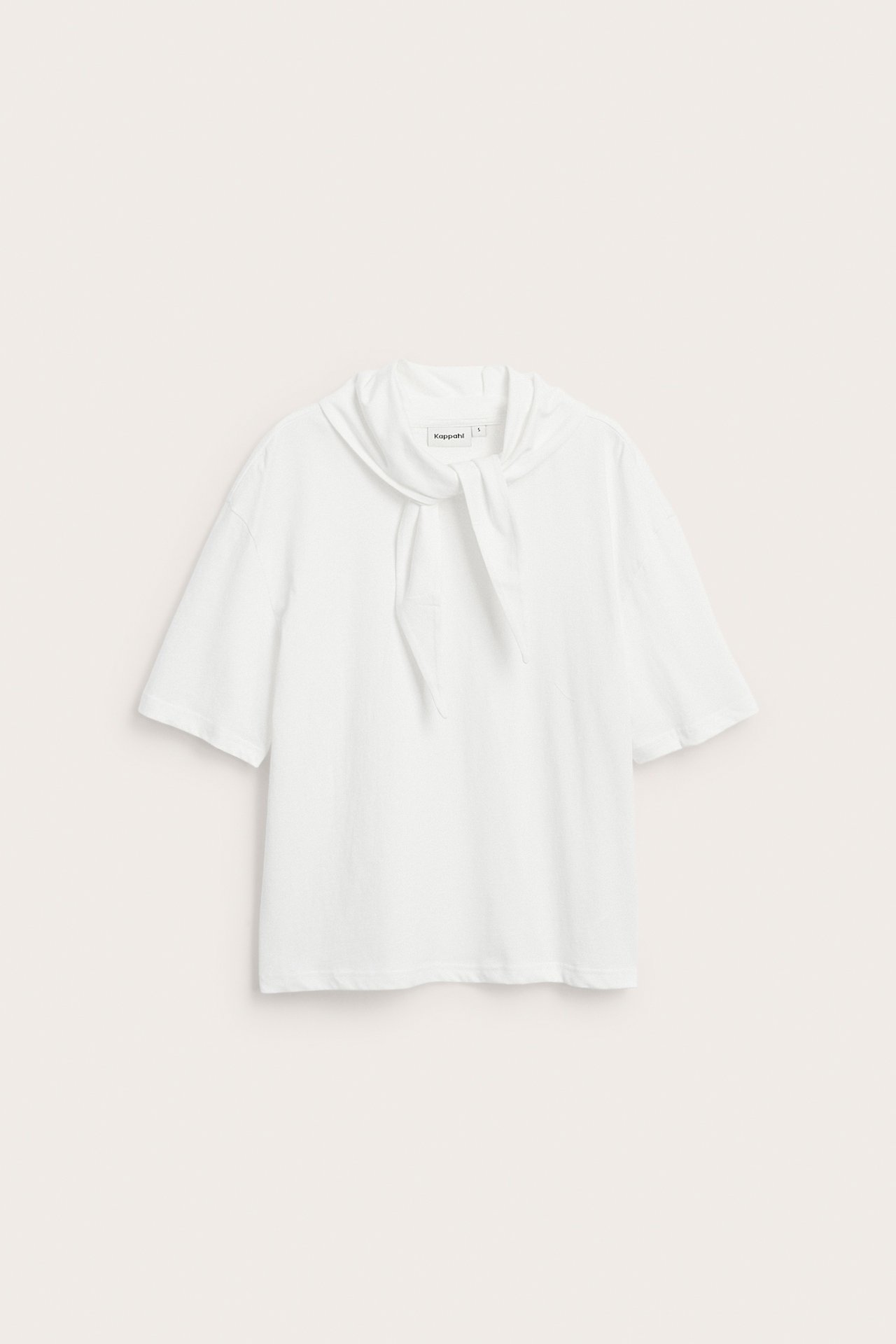 Frontvy av en offwhite kortärmad bomulls-t-shirt med en fastsatt sjaldetalj knuten vid halsen.