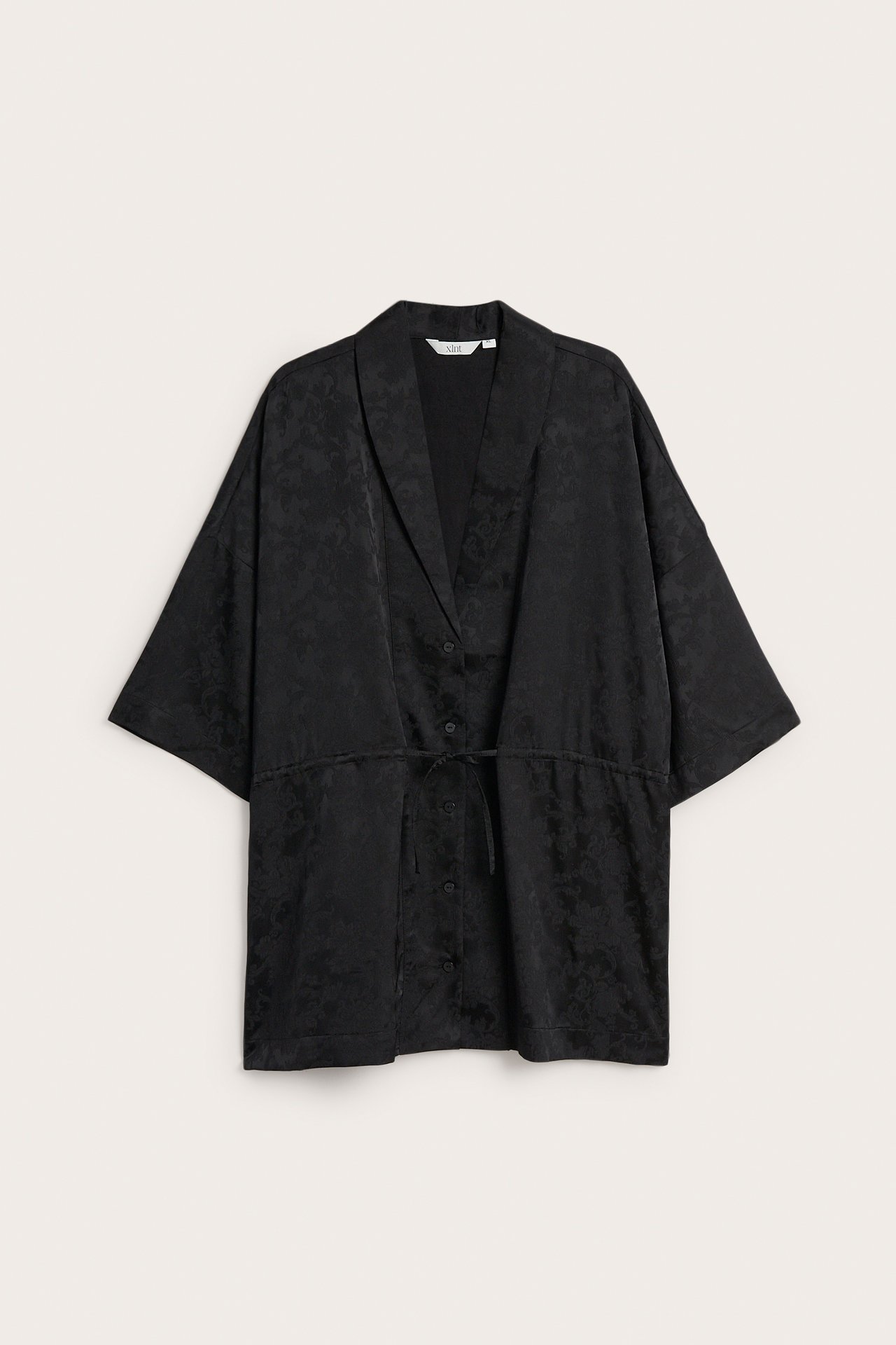 Forfra: Svart mønstret kimono-topp med knapper og snøring i midjen.