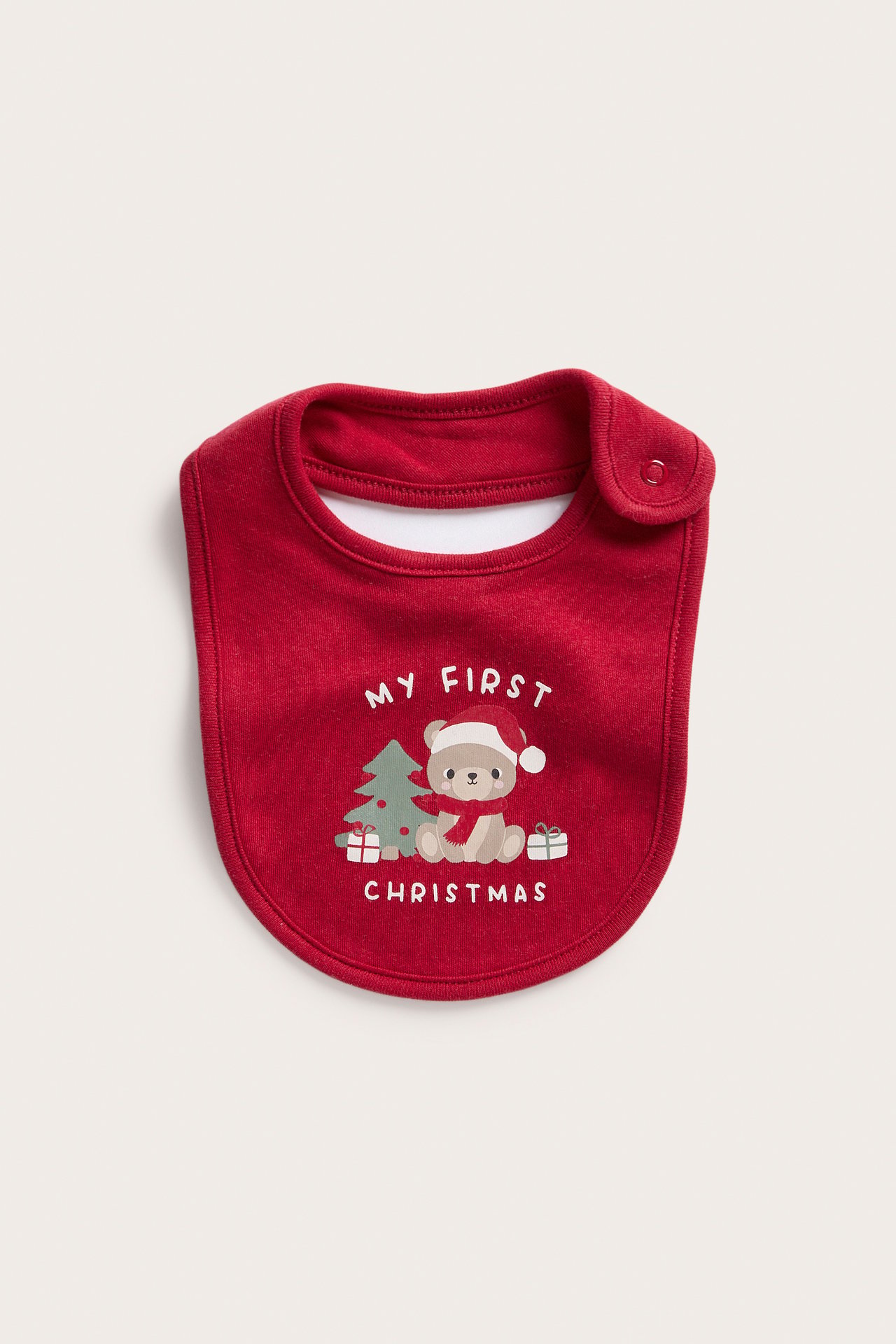 Widok z przodu czerwonego śliniaka dla niemowląt z napisem 'MY FIRST CHRISTMAS' i zapięciem.