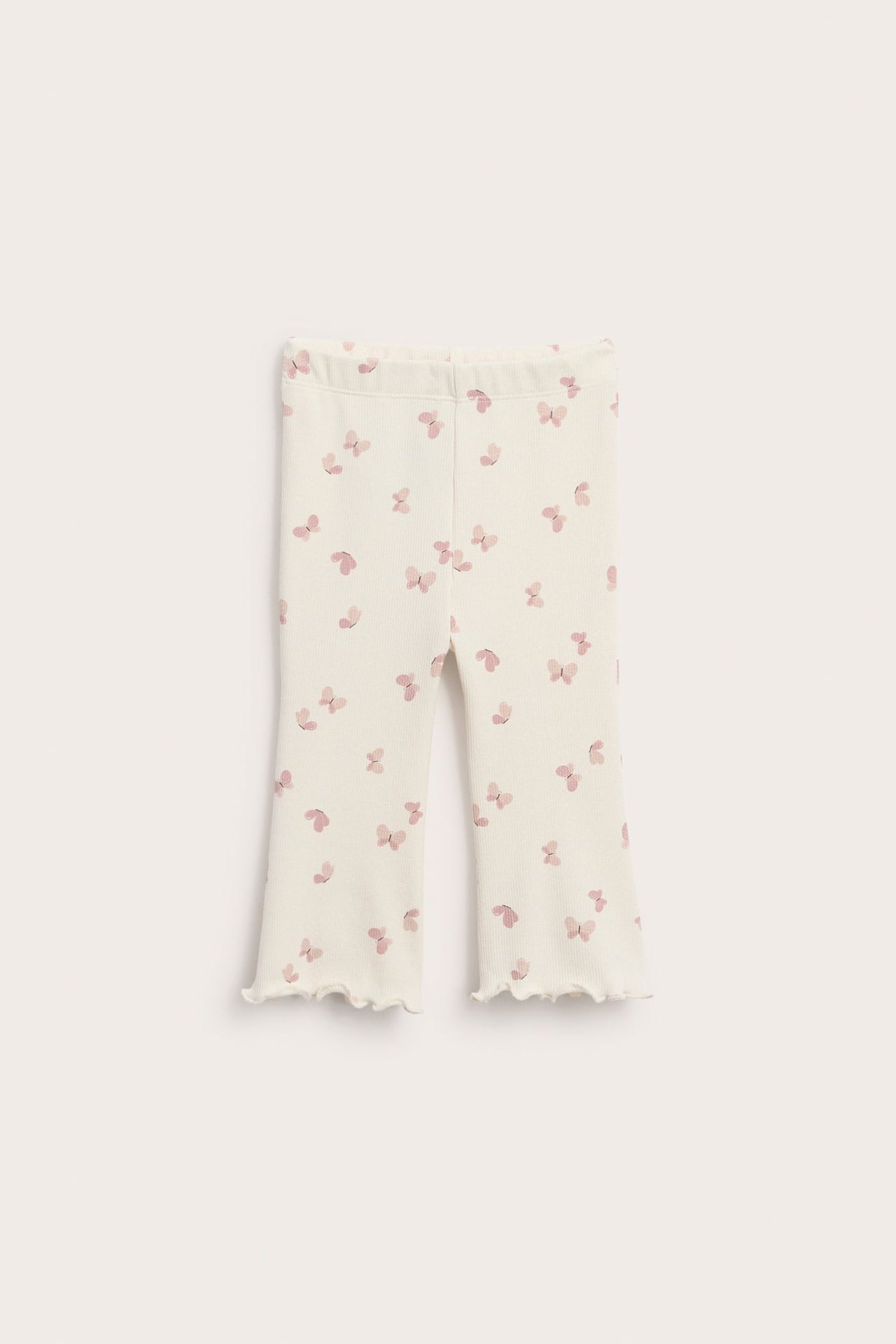 Frontvy av offwhite ribbade utsvängda leggings med rosa fjärilsmönster och vågiga benslut.