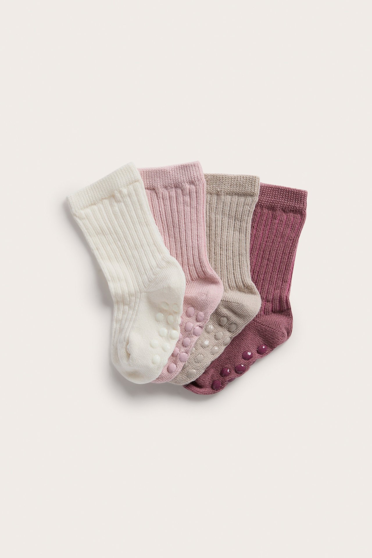Ovenfra fire ribbestrikkede babysokker med antiskli i krem, rosa, taupe og burgunder.