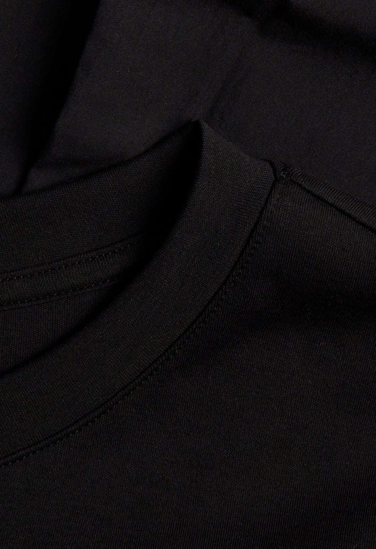 Närbild av en svart kort t-shirtklänning i bomullstrikå som visar den ribbade rundhalsen.