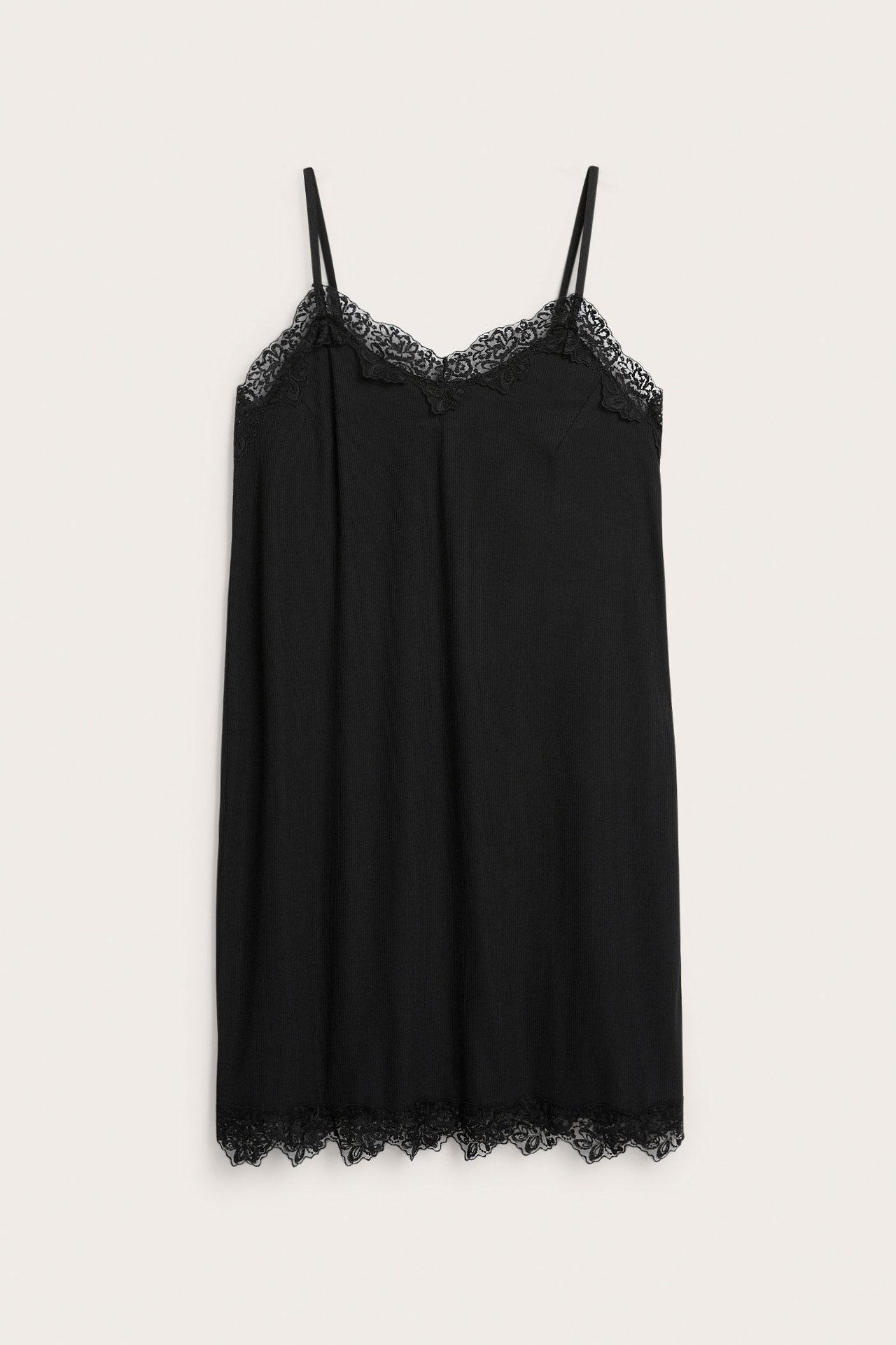 Edestä kuvattu musta trikoo alusmekko, jossa ohuet olkaimet ja pitsikoristelu pääntiessä sekä helmassa.