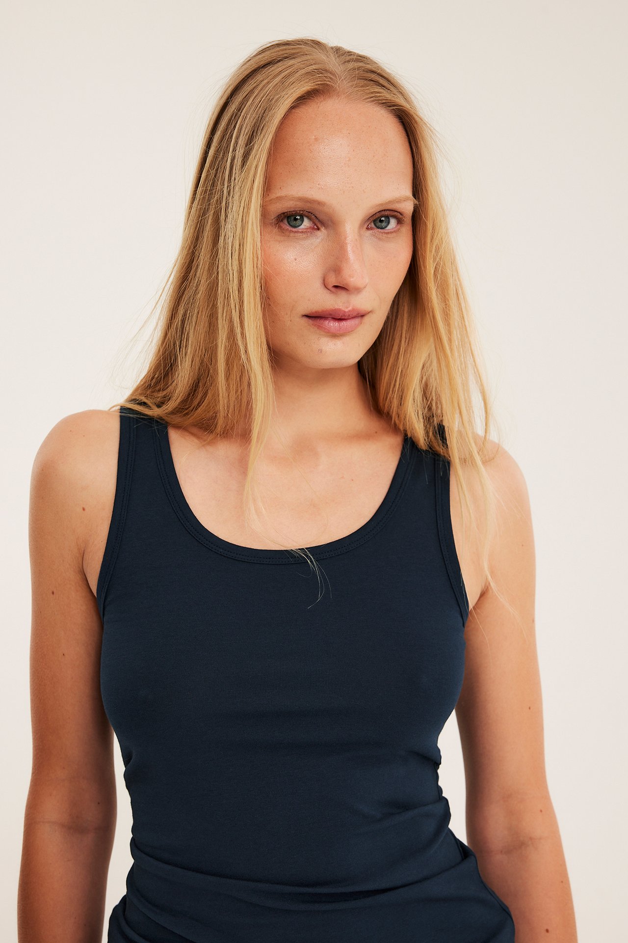 Lähikuva edestä: nainen yllään tummansininen joustava puuvillatrikootoppi.