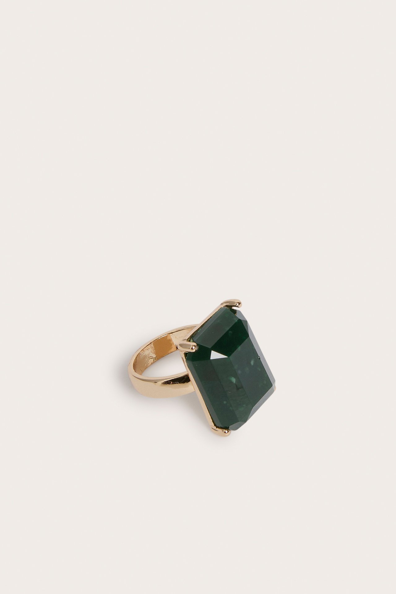 Närbild av en guldfärgad ring med en stor smaragdslipad mörkgrön sten.