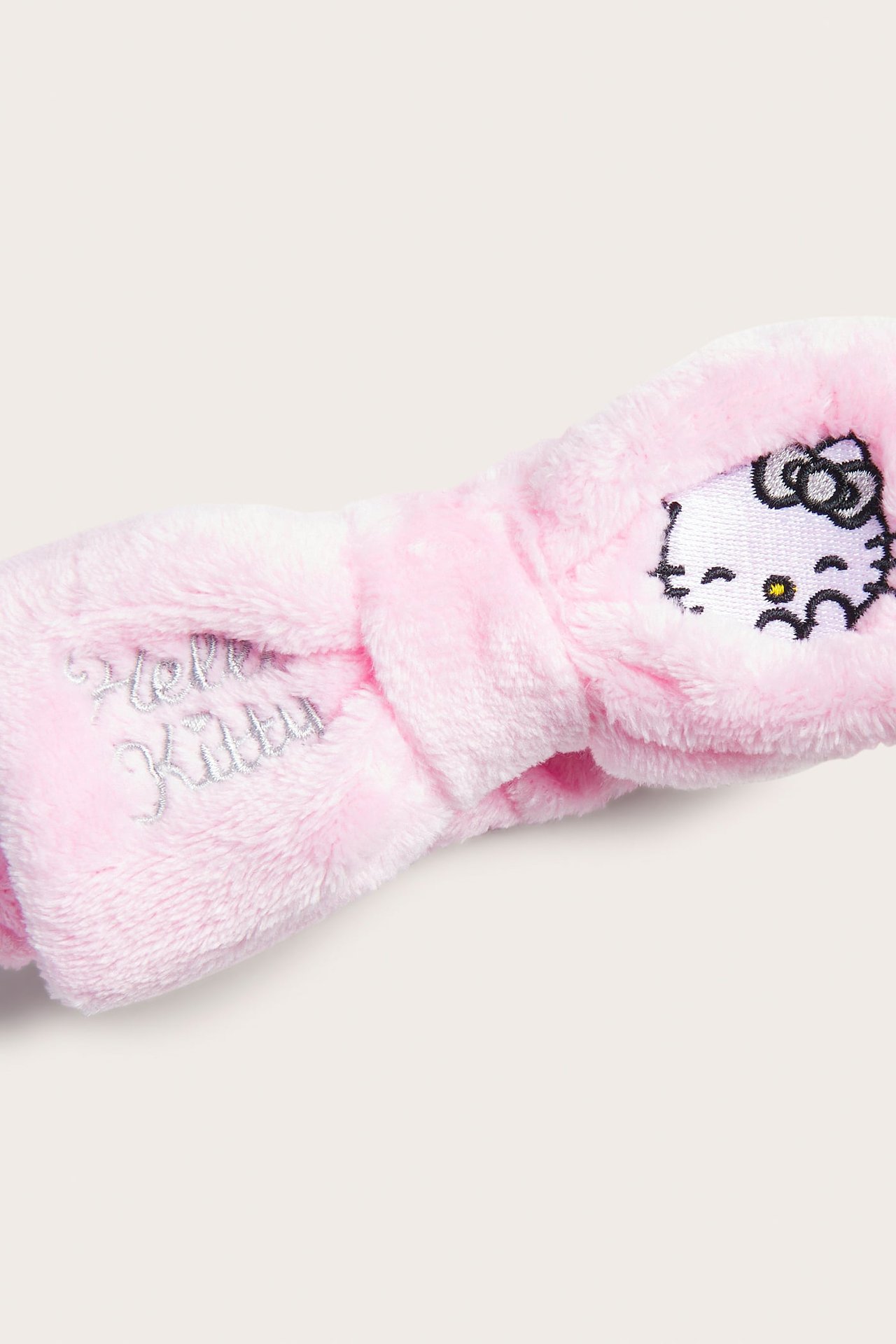 Zbliżenie na różową, puszystą opaskę Hello Kitty z haftowanymi detalami.