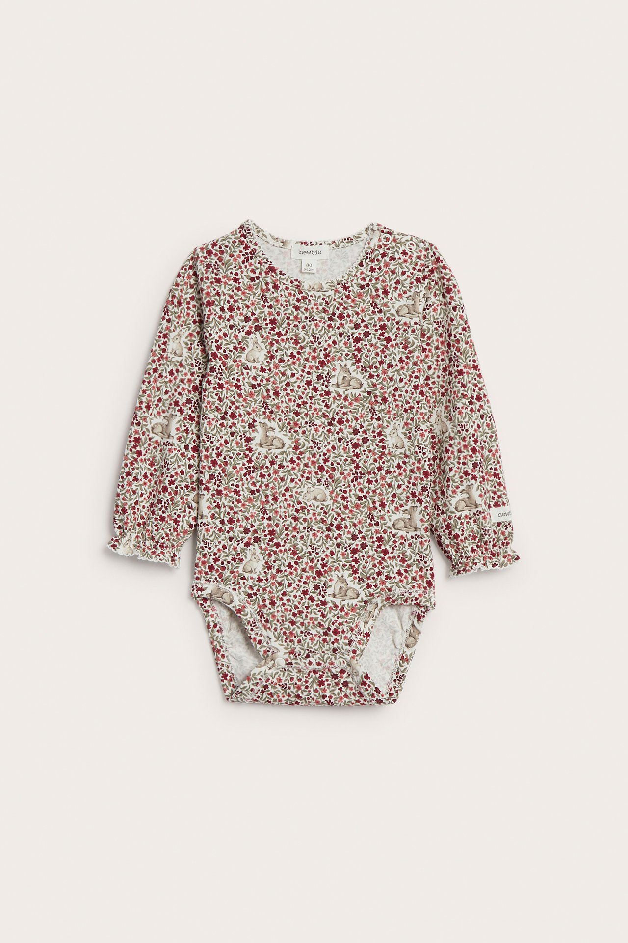 Frontvy, babybody i krämvitt med lång ärm, rött blommigt, kaninmönster och volangärmslut.