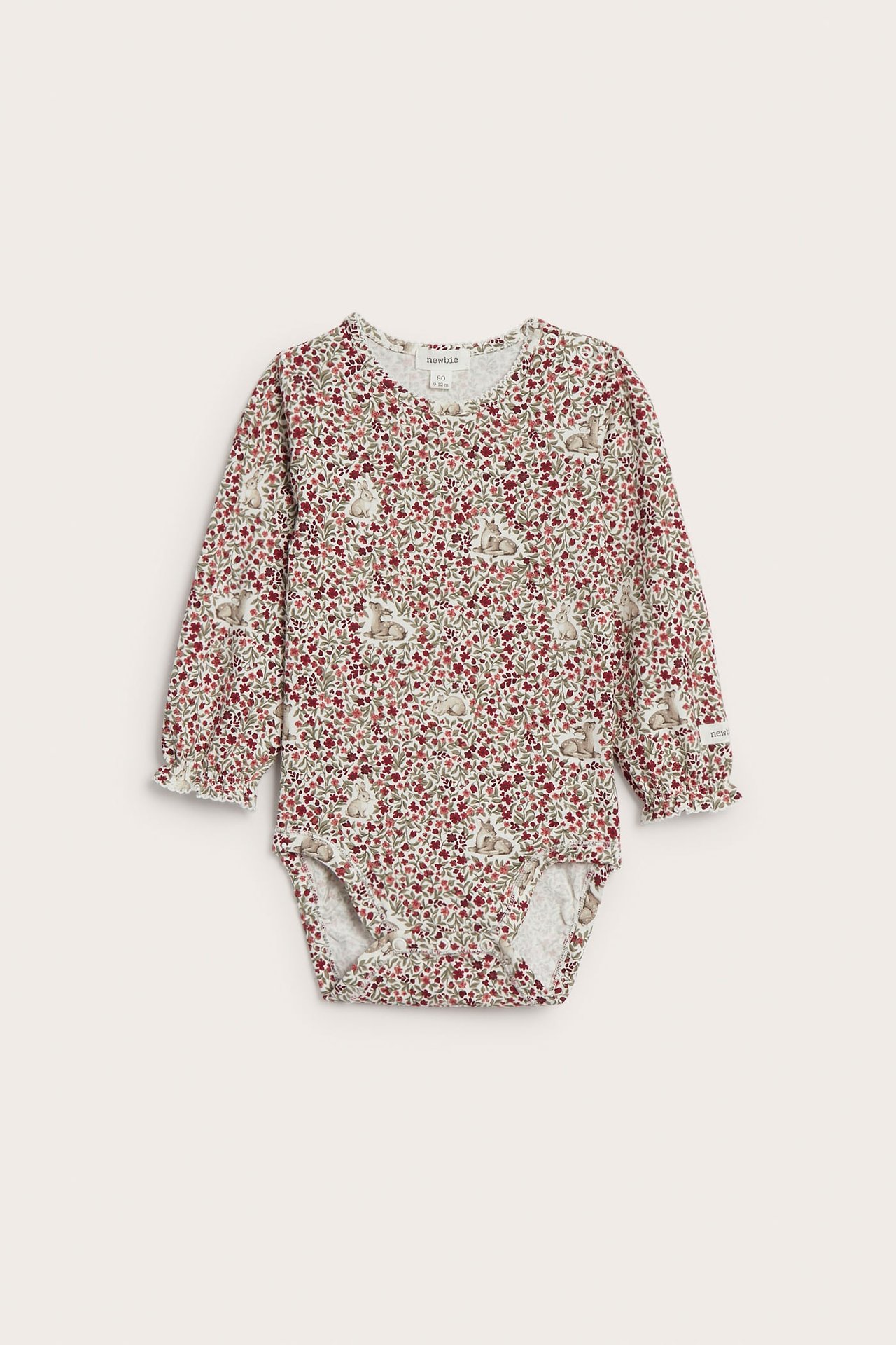 Frontvy, babybody i krämvitt med lång ärm, rött blommigt, kaninmönster och volangärmslut.