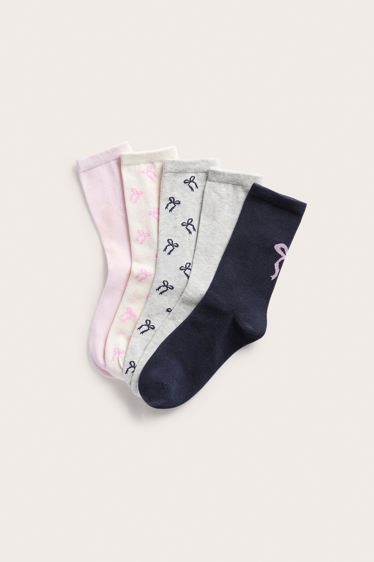Fem sokker: marineblå med rosa sløyfe, rosa, kremhvit med sløyfer, og to grå med sløyfer.