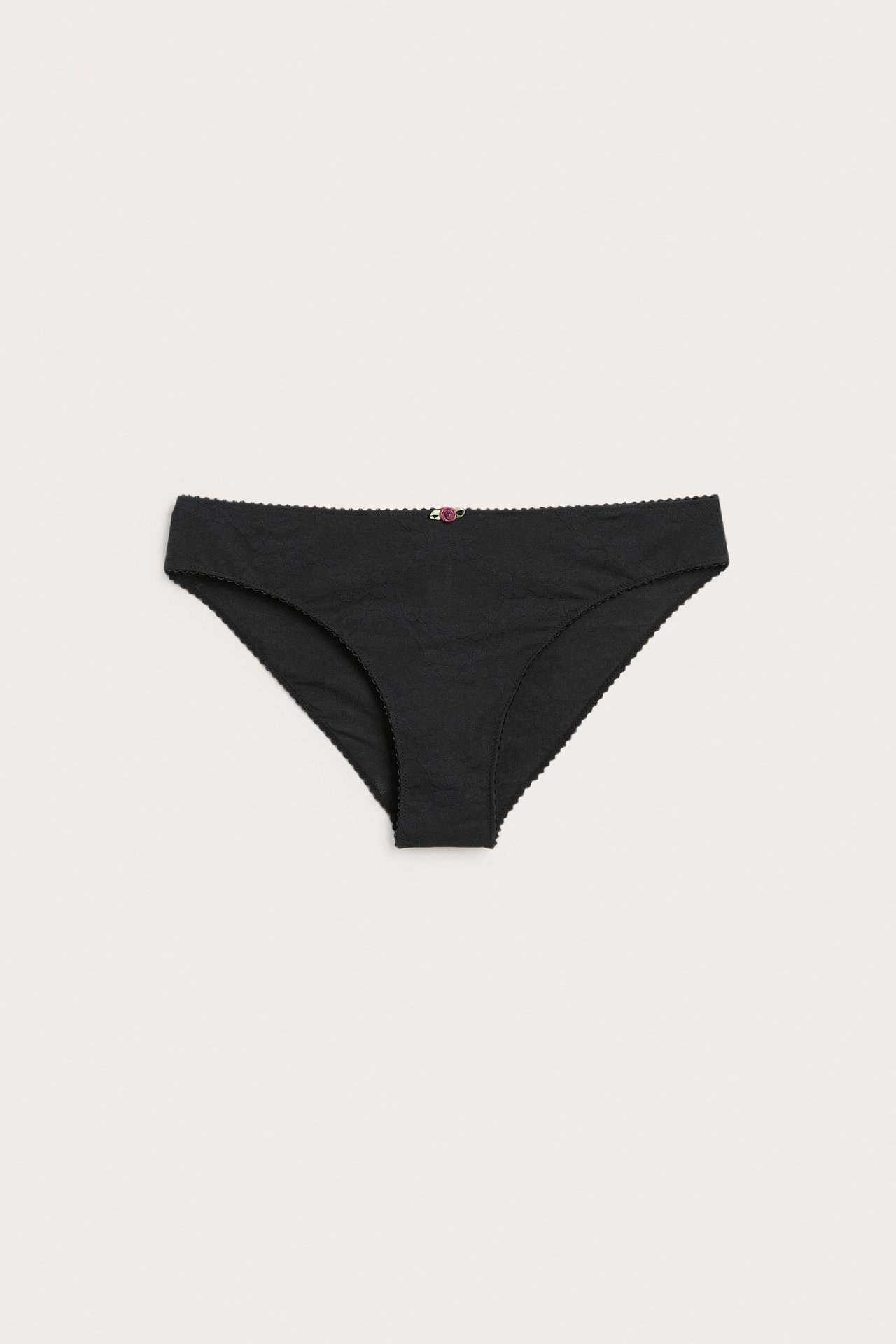 Framifrån, svarta dambriefs med en liten rosa blomdetalj.