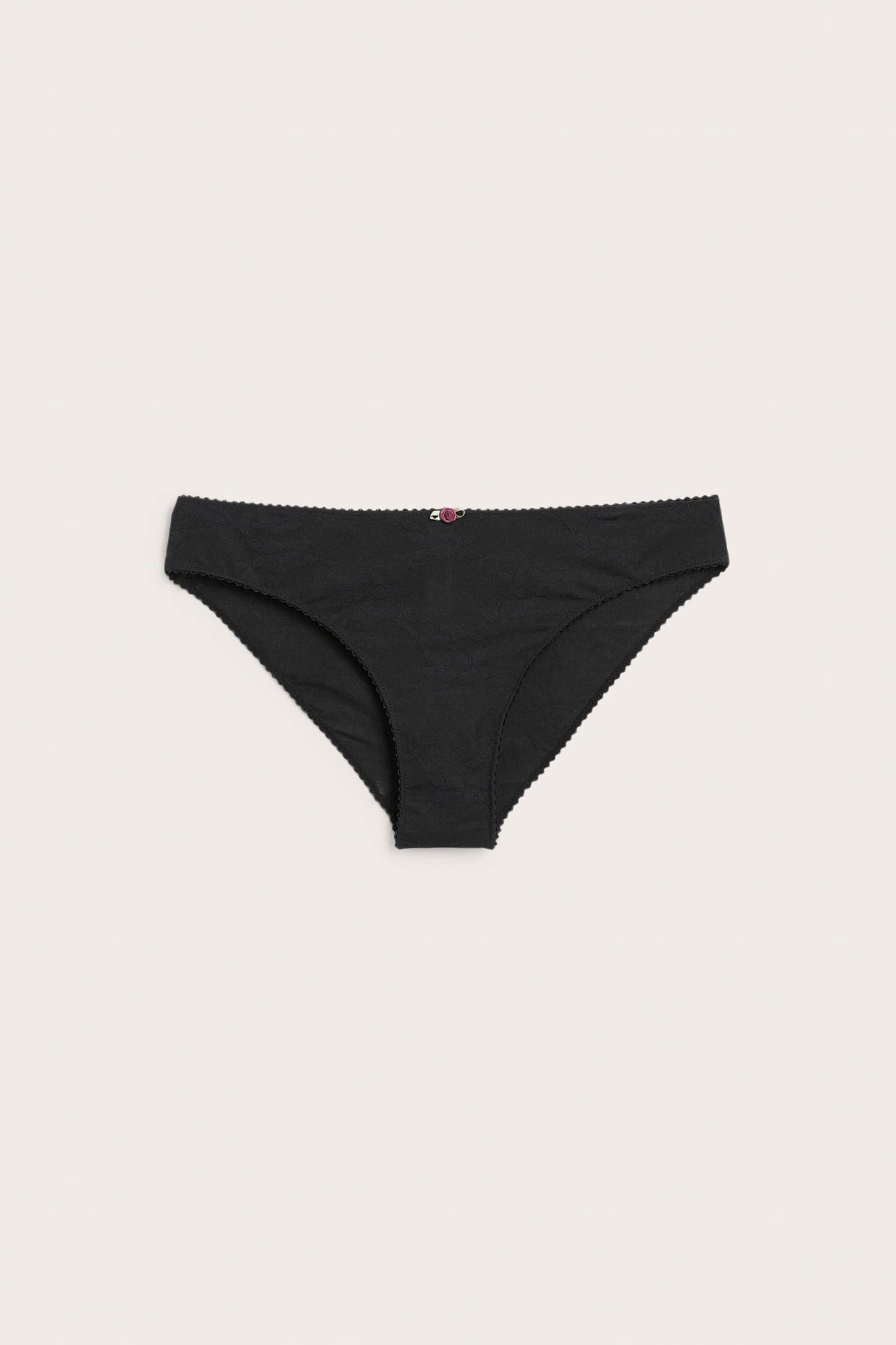 Framifrån, svarta dambriefs med en liten rosa blomdetalj.