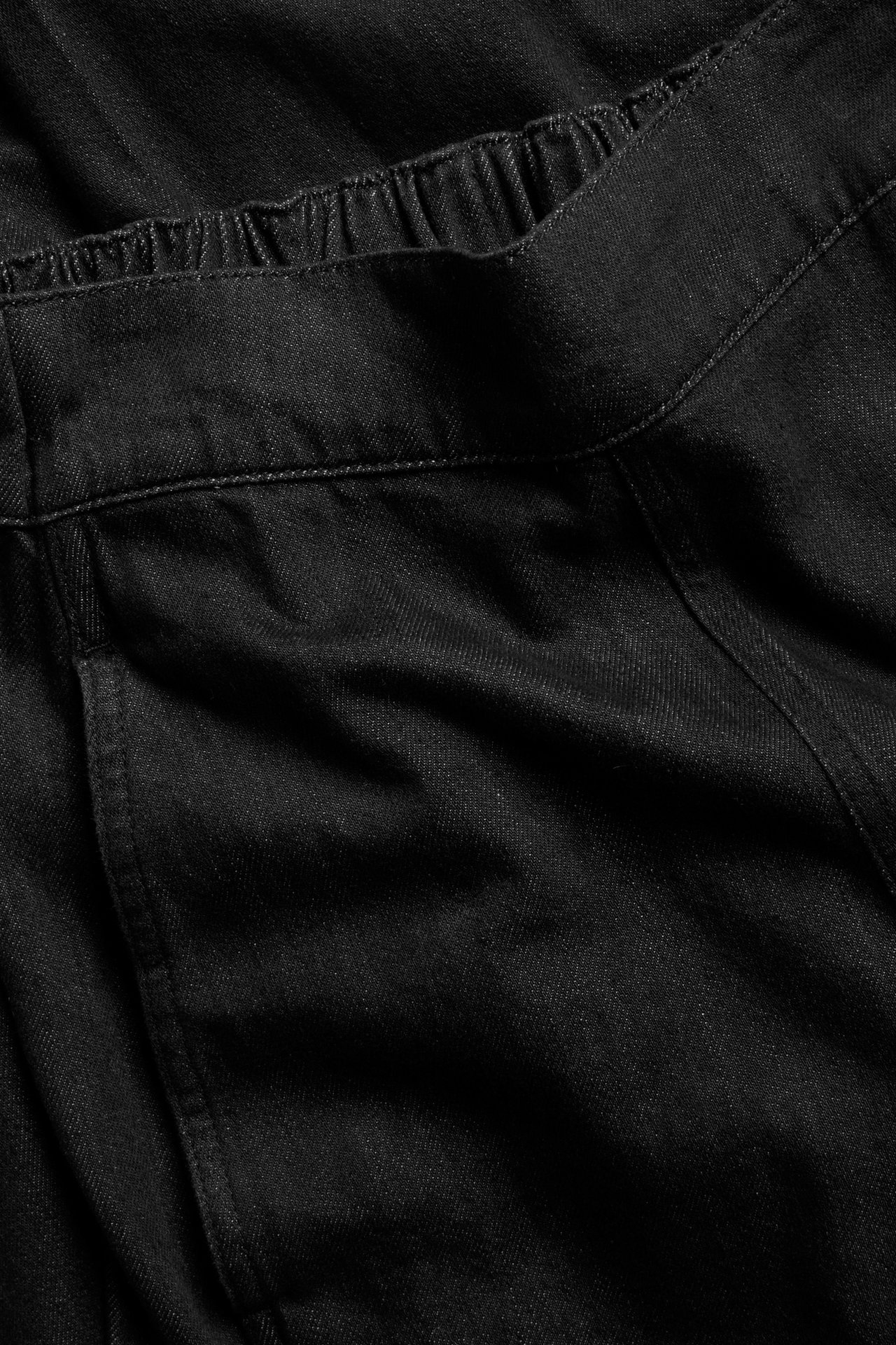 Lähikuva mustista denim barrel fit -vetofarkuista, joissa joustava vyötärö ja sivutasku.