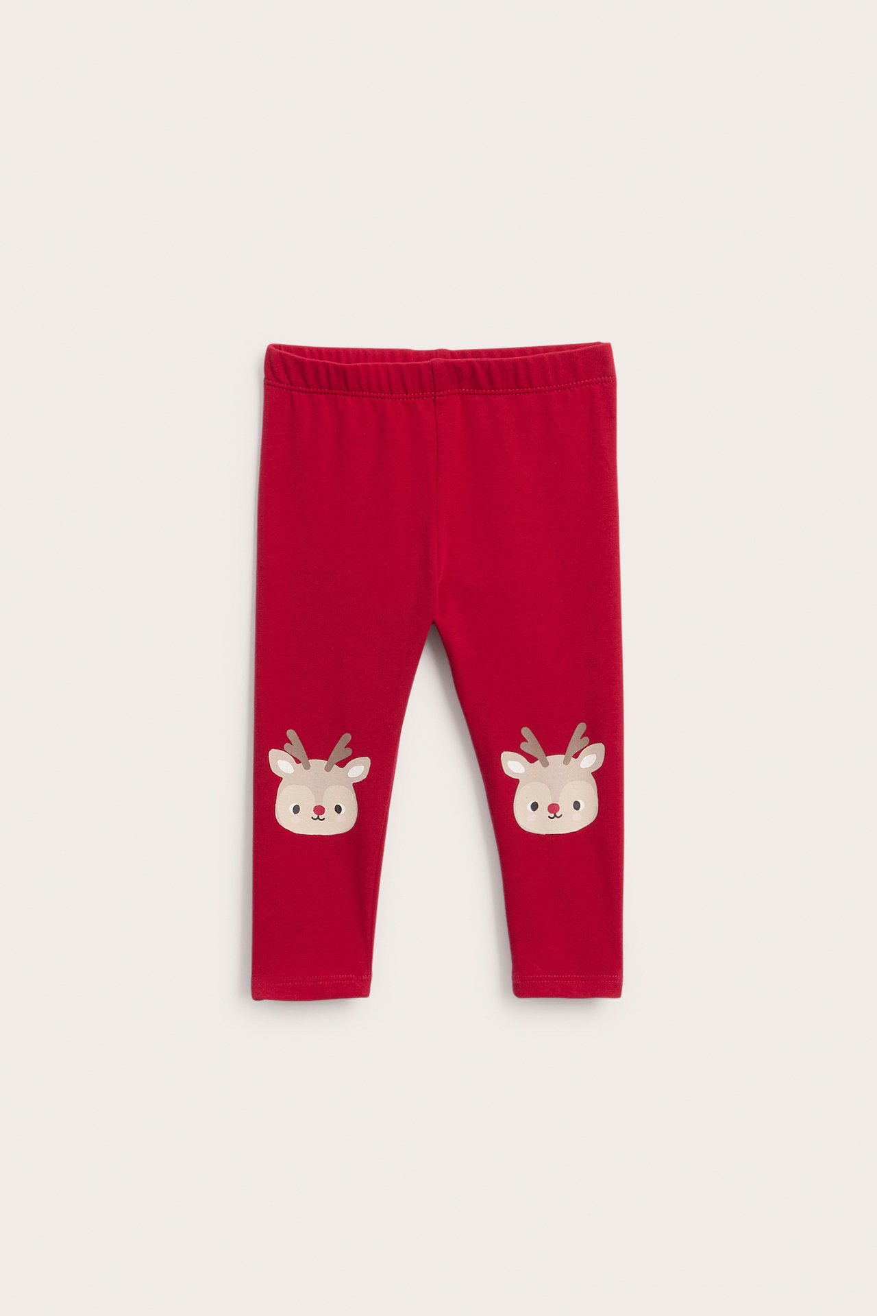 Framifrån röda baby leggings med tecknade renlappar på knäna.