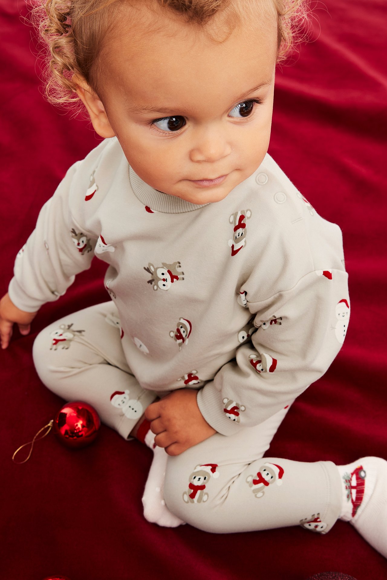 Högvinkelbild av bebis i beigefärgad pyjamas med jultryck.