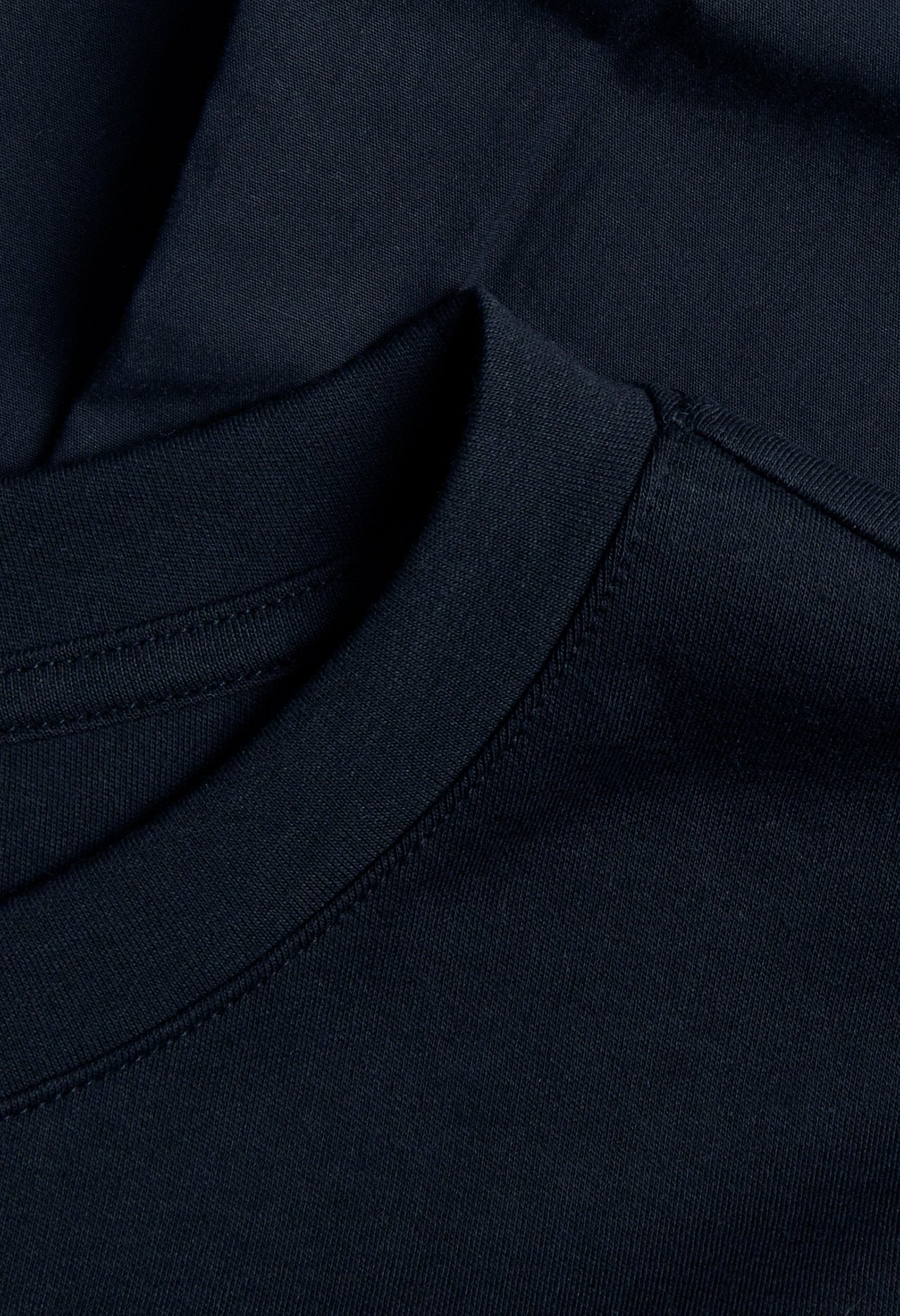 Lähikuva tummansinisestä puuvillaisesta t-paitamekosta, jossa on pyöreä pääntie.