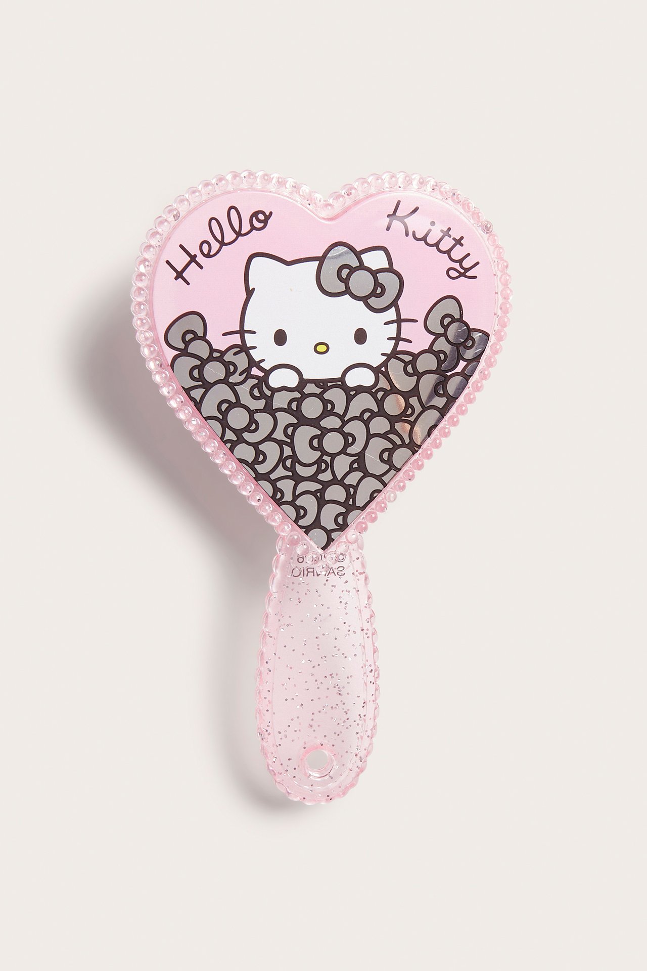 Framifrån, rosa hjärtformad Hello Kitty-spegel med glitterhandtag och små rosetter.