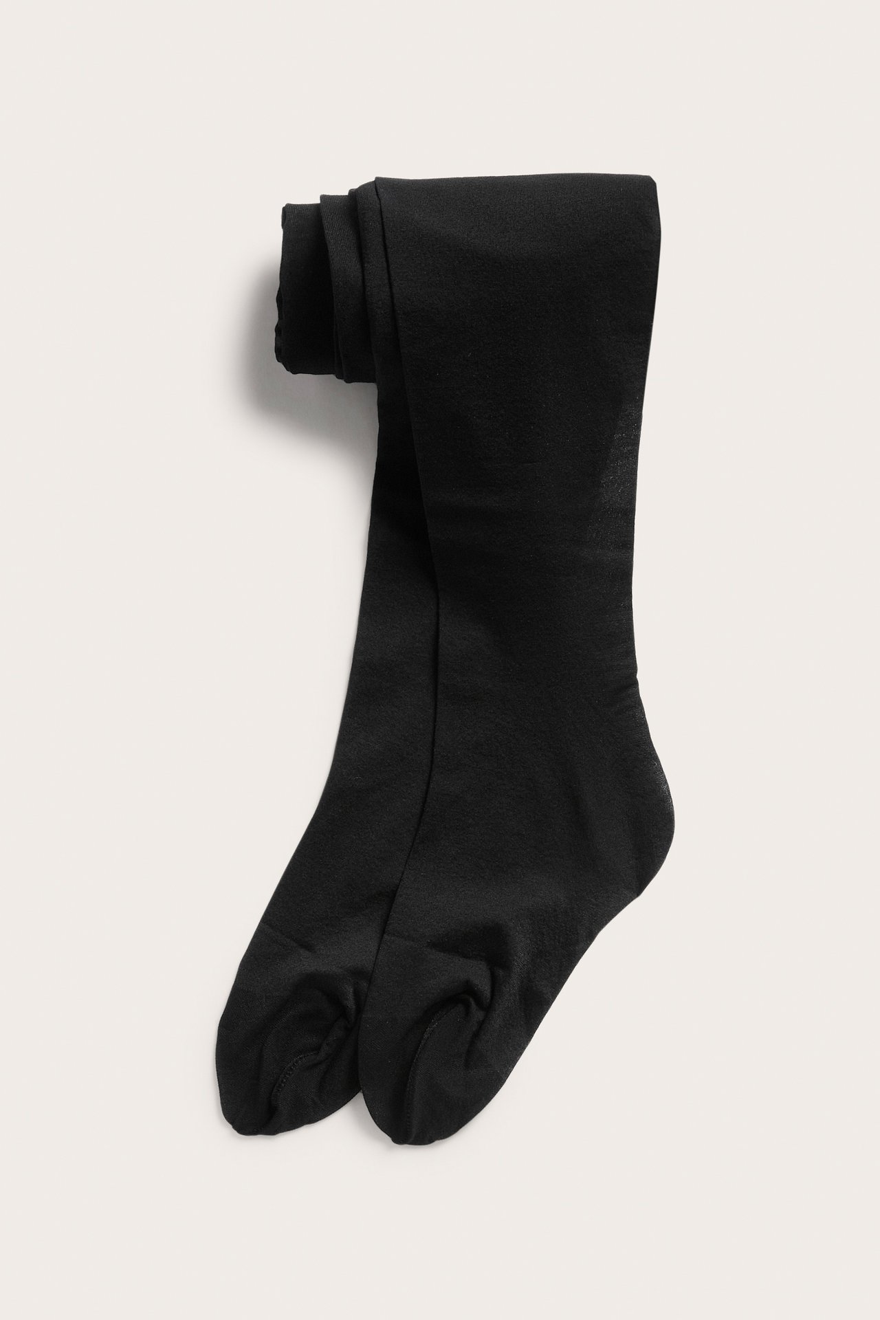 Mustat taitetut läpinäkymättömät sukkahousut, edestä.