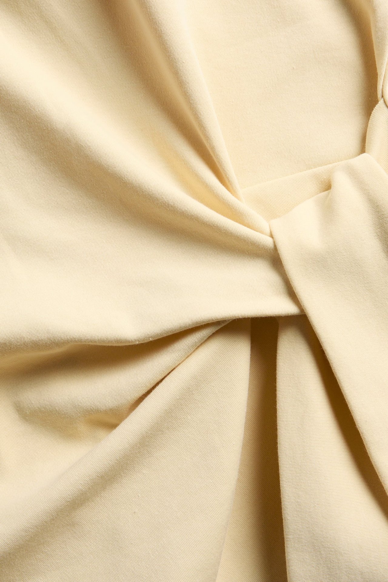 Zbliżenie na jasnożółty materiał z wiązanym detalem.