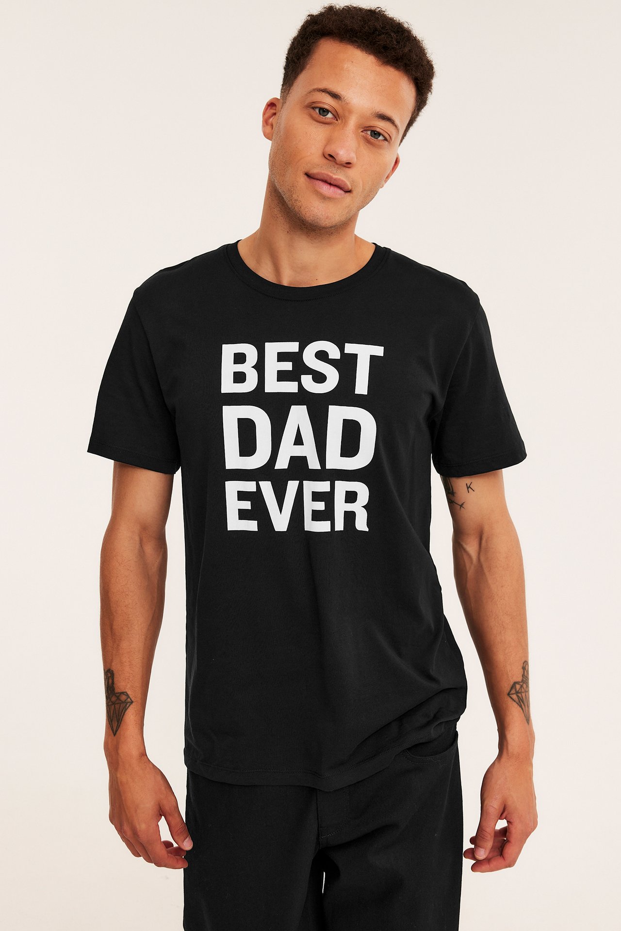 Framsida av en man i svart t-shirt med texten 'BEST DAD EVER' och svarta byxor.