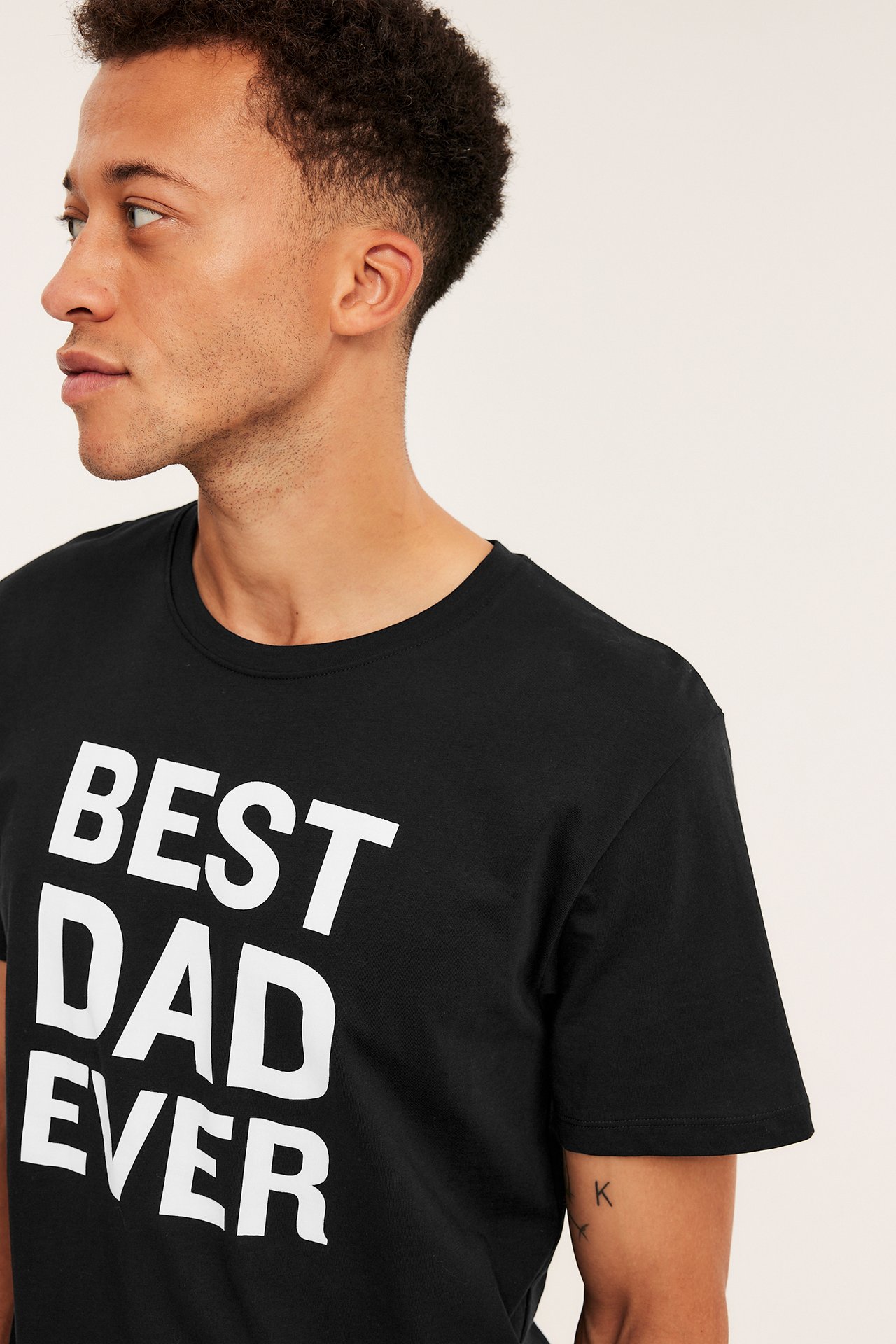 Närbild i sidoprofil på en manlig modell som bär en svart t-shirt med texten "BEST DAD EVER".