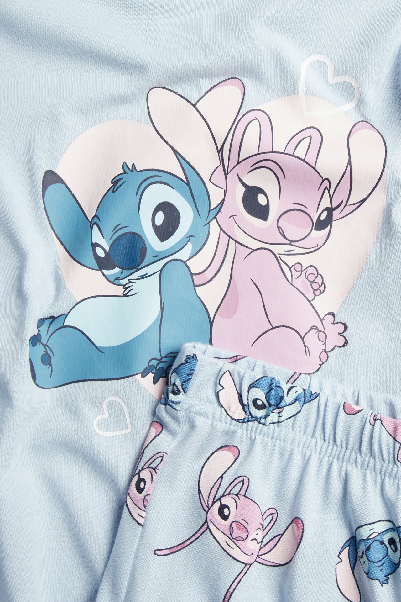 Nærbilde av et lyseblått pyjamassett med Stitch- og Angel-motiver.