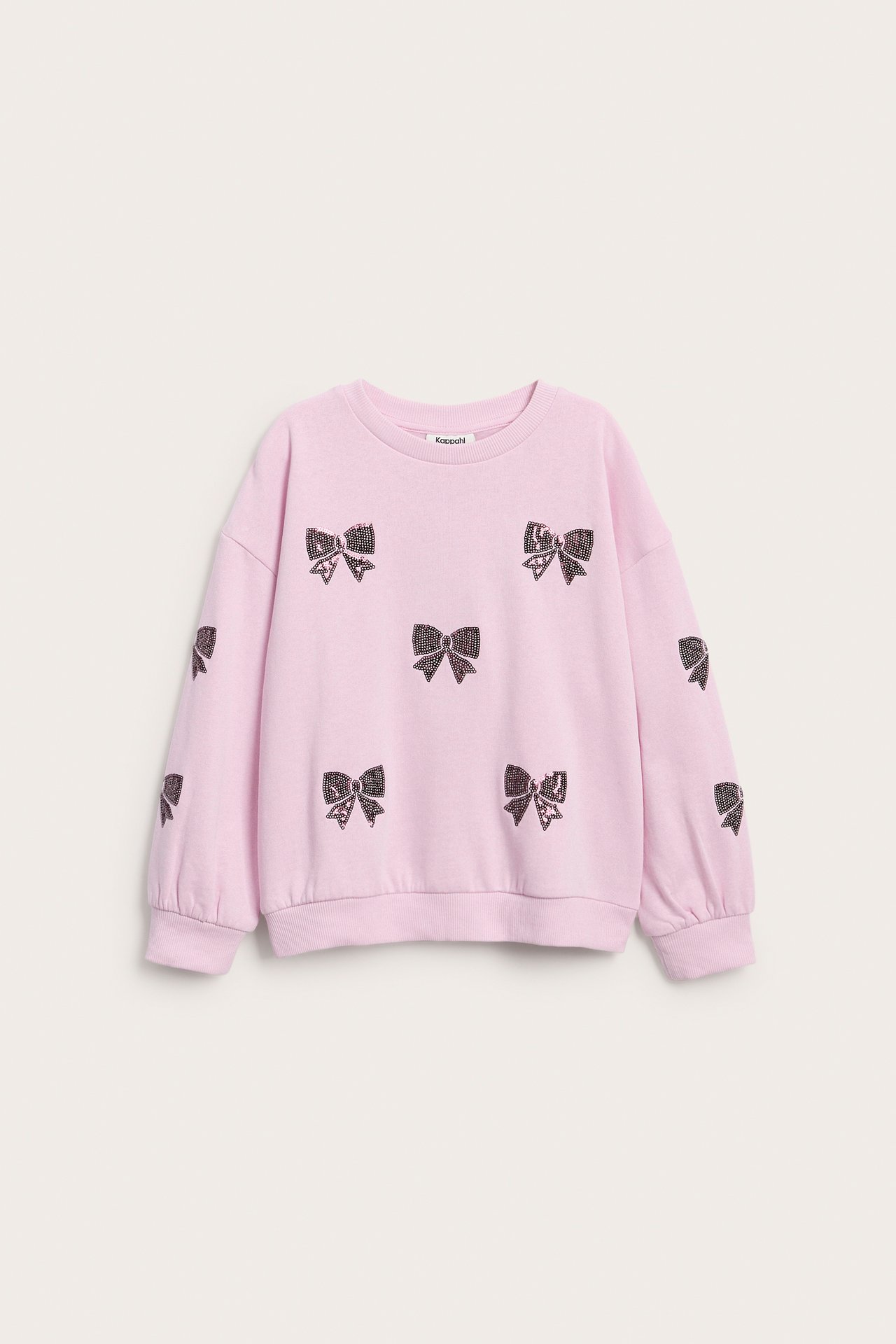 Frontvy av en rosa långärmad barntröja med mörka paljettrosetter.