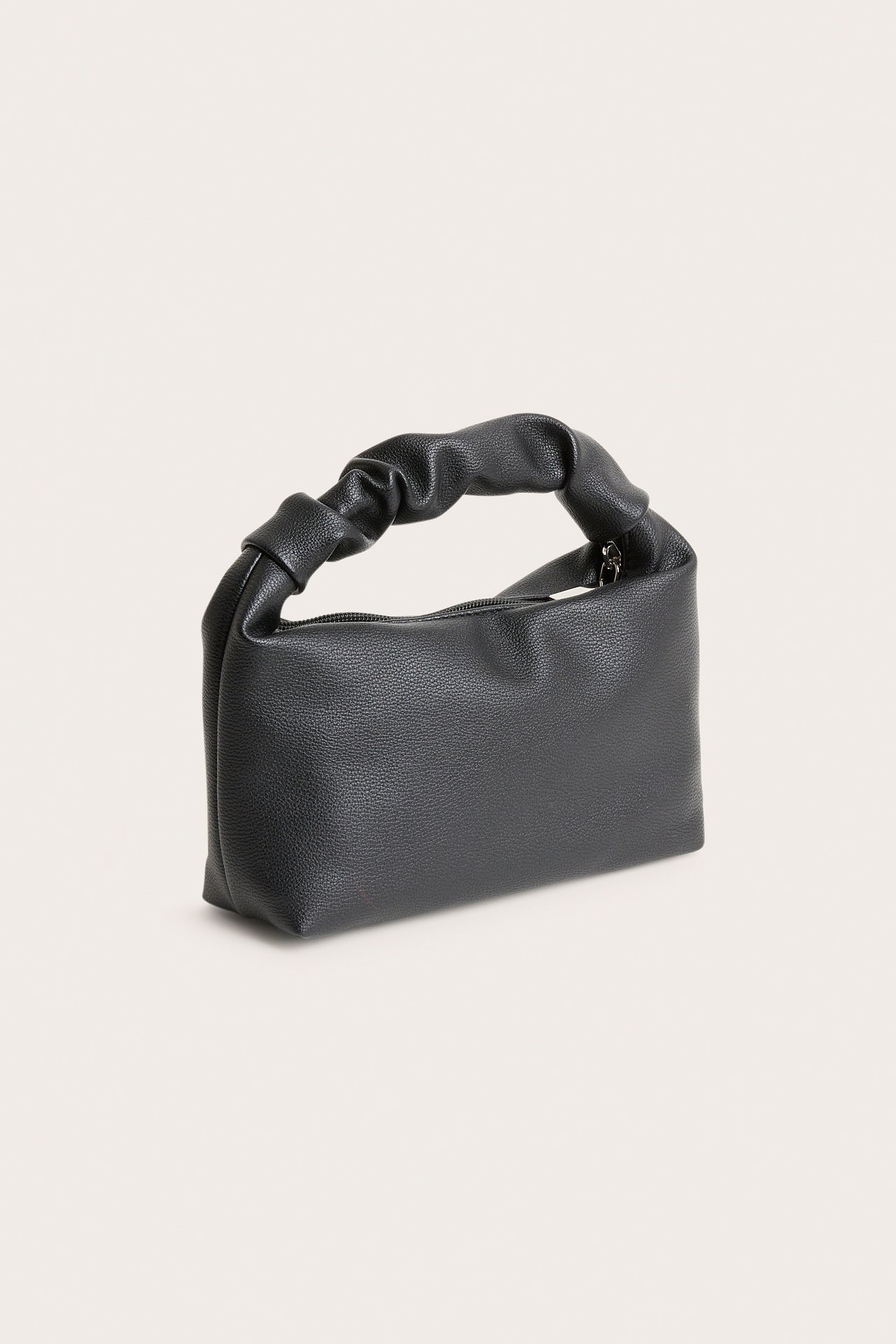 Musta teksturoitu käsilaukku, jossa on rypytetty kahva ja vetoketju, sivukuva.