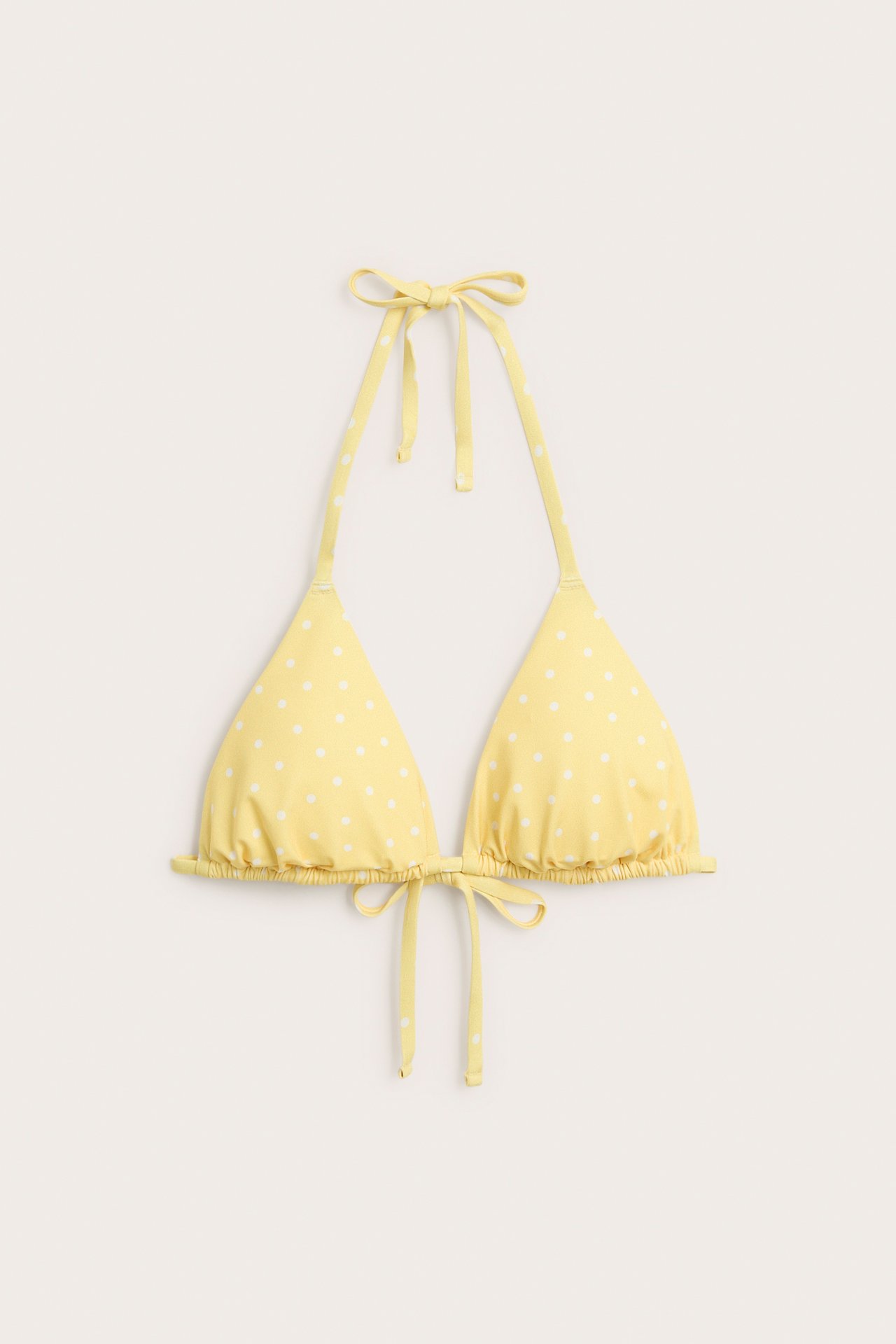 Forfra gult prikkete trekant-bikini overdel med knytebånd i nakken og ryggen.