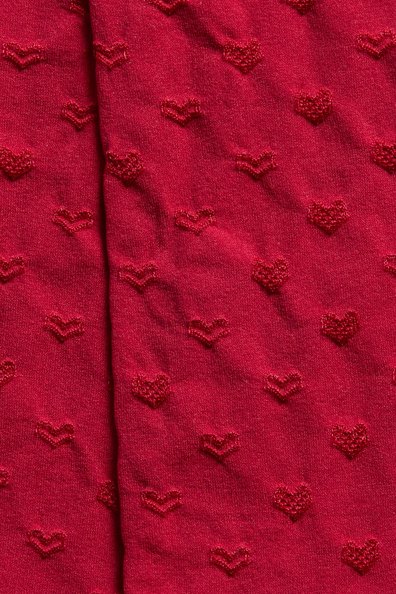 Närbild på ett rött tyg med texturerat hjärtmönster.