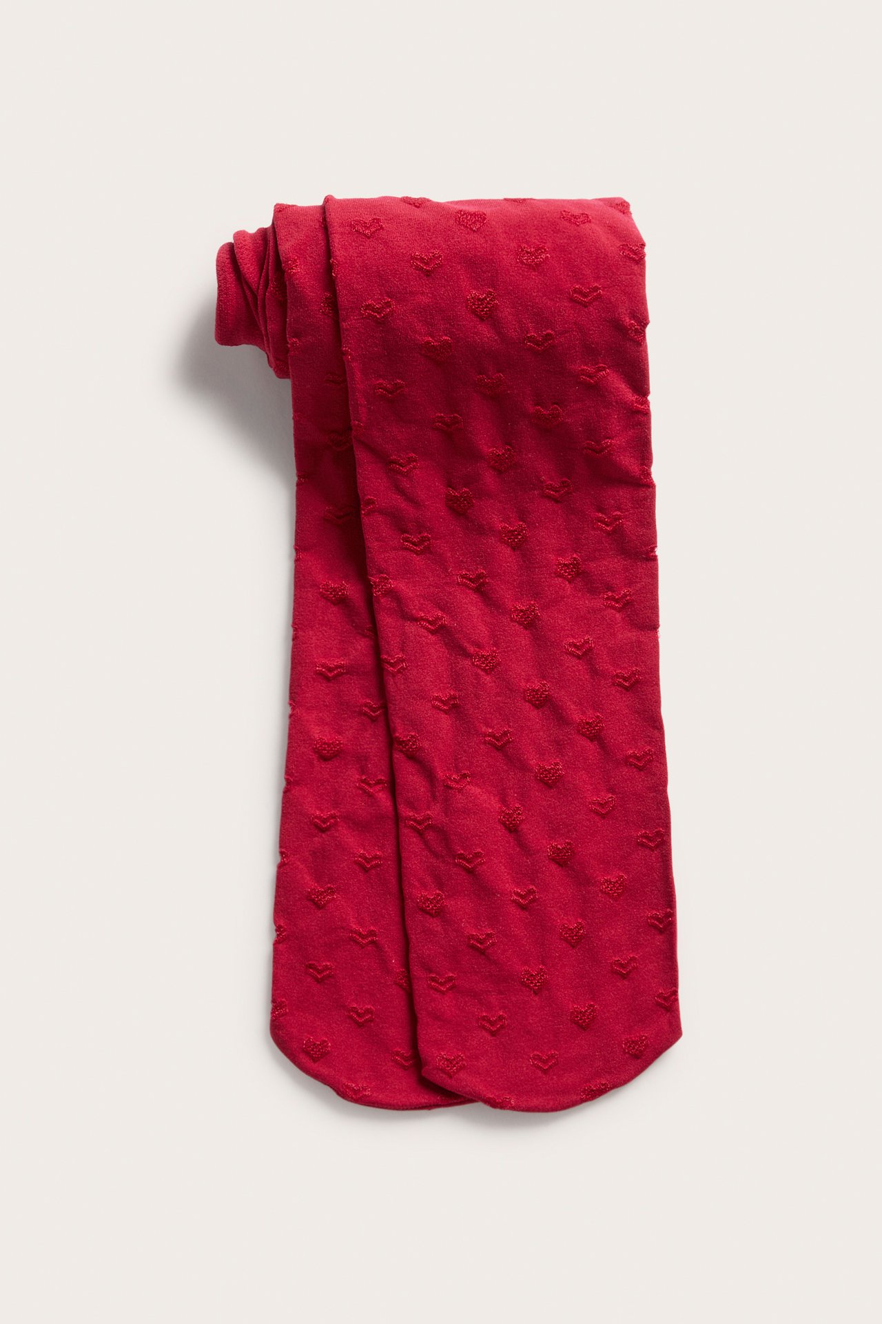 Plattvy av röda strumpbyxor med texturerat hjärtmönster, vikta.