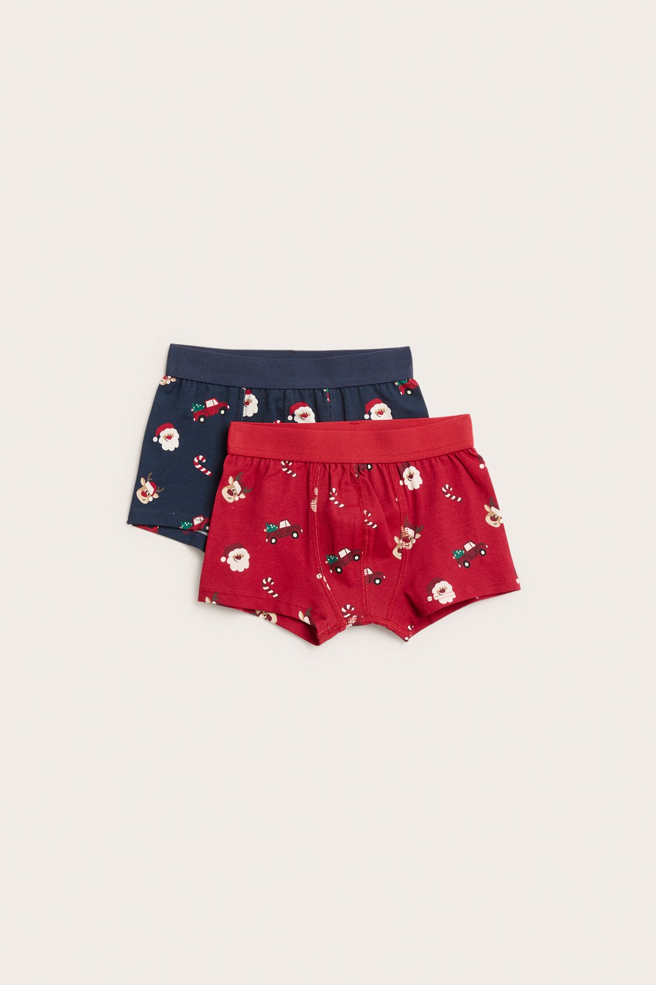 Frontutsikt av barns røde og marineblå boxershortser med julenisse, reinsdyr og lastebilmønster.