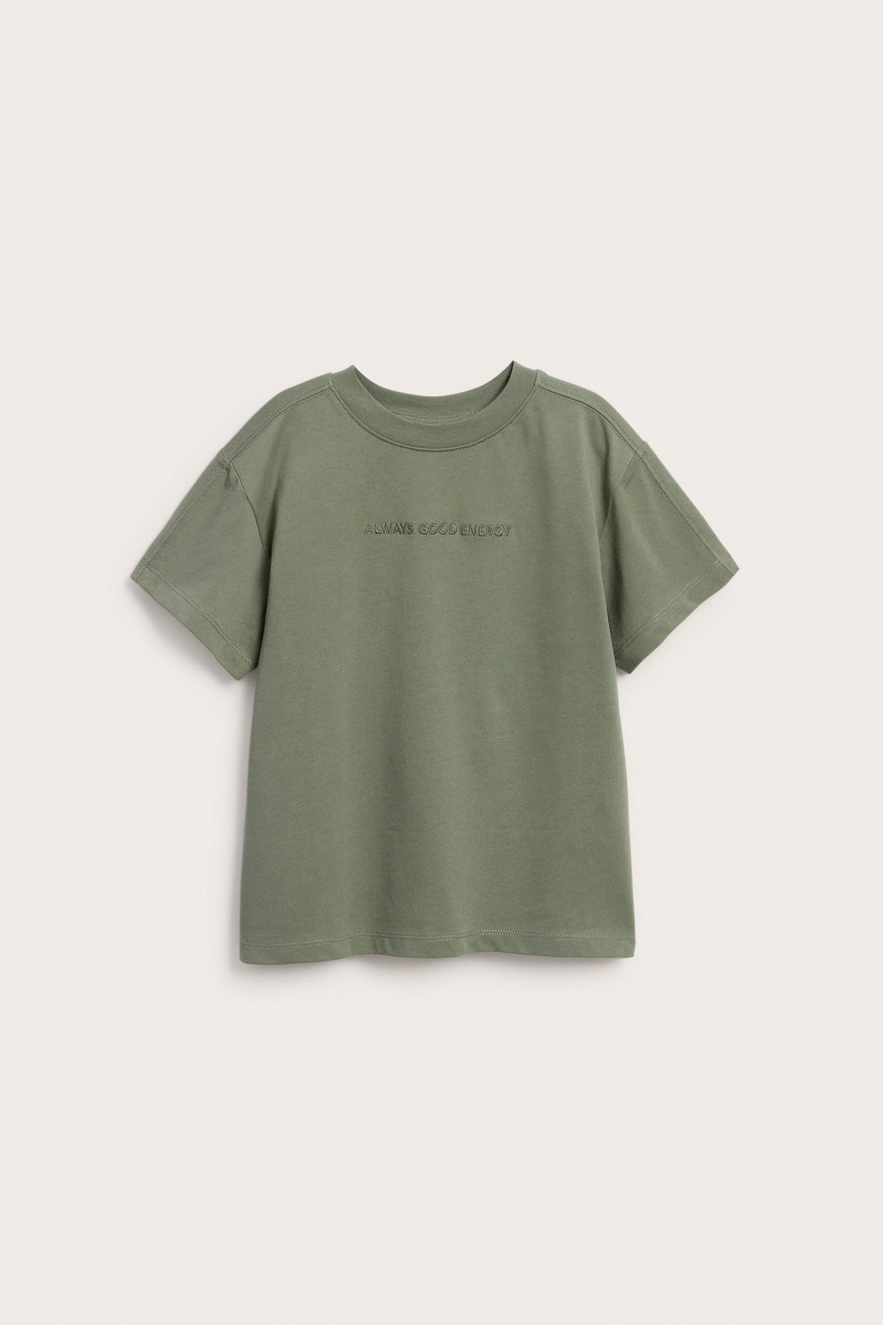 Framsida av en grön kortärmad t-shirt med texten "ALWAYS GOOD ENERGY" broderad på bröstet.