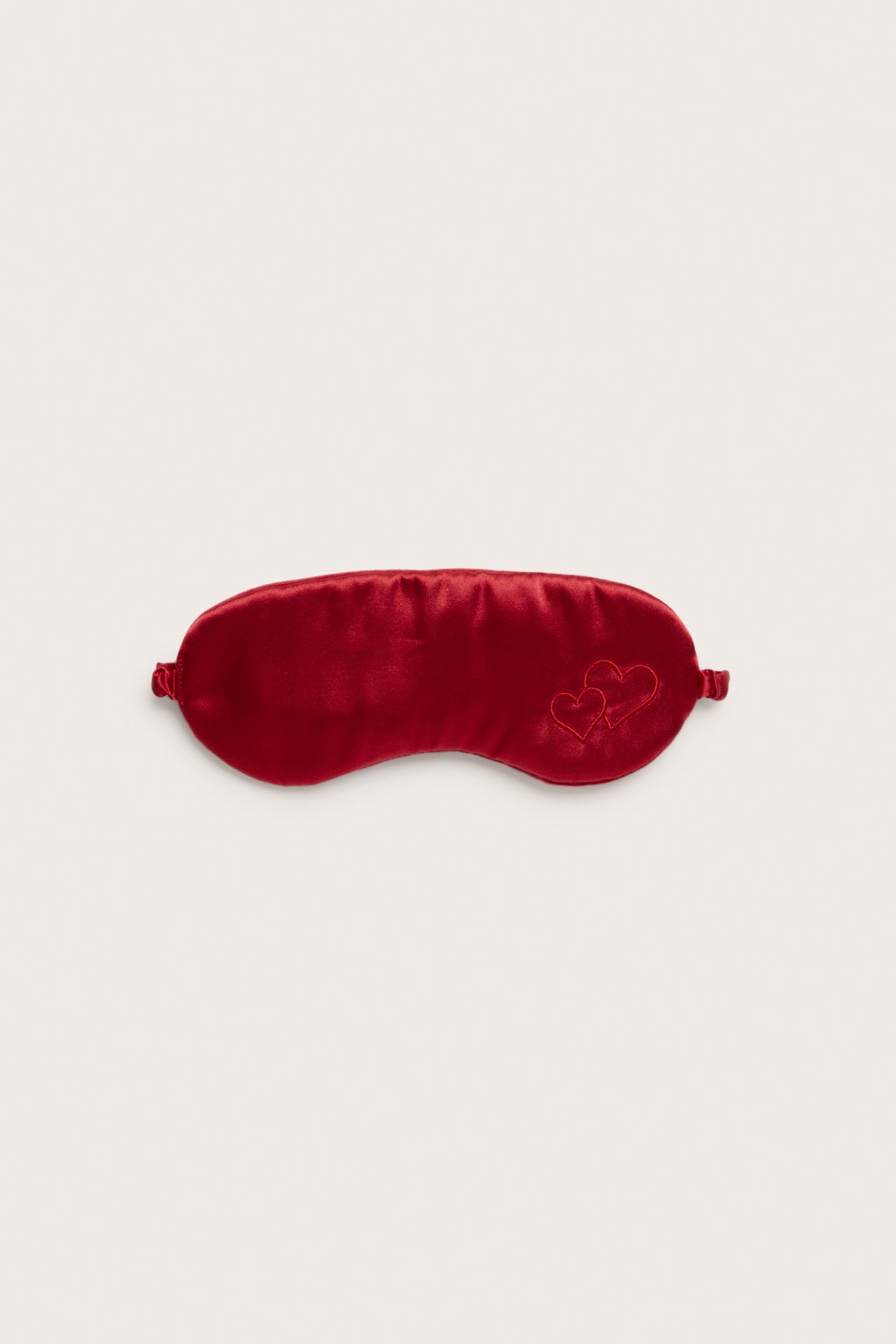 Ovanifrån, röd ögonmask i satin med två broderade hjärtan.
