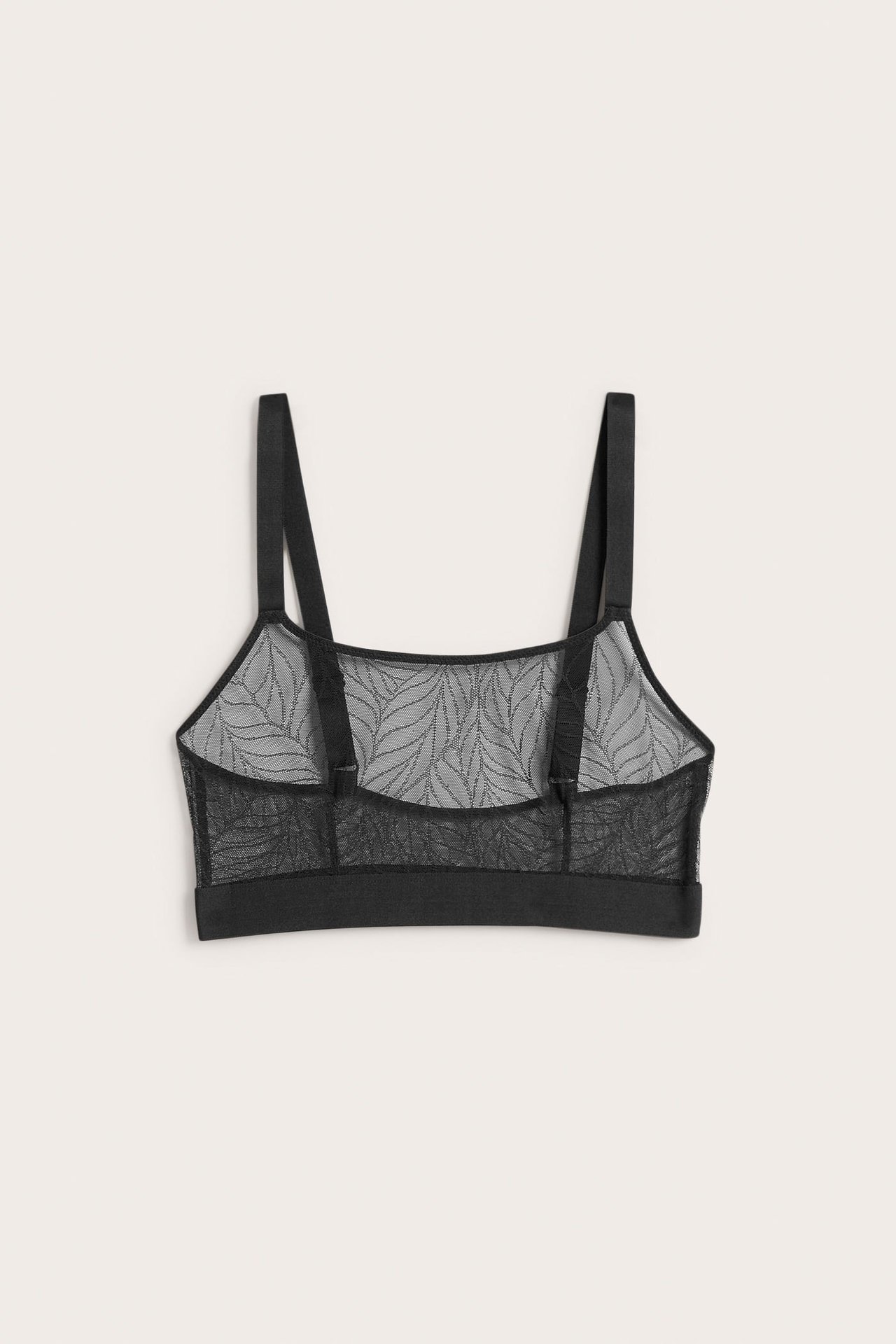Bakifrån av en svart skir bralette med bladmönster och justerbara axelband.