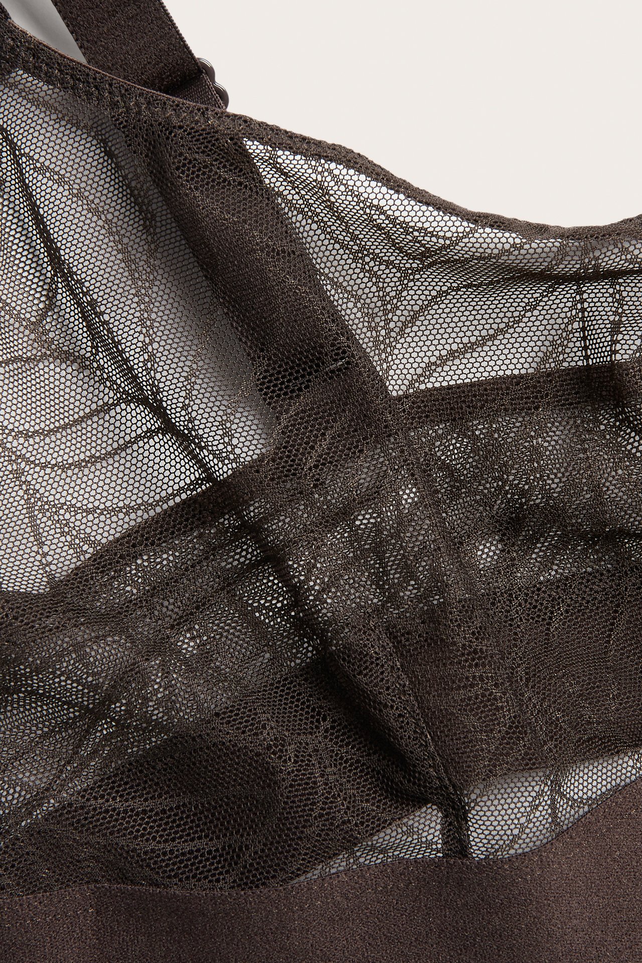 Närbild av en mörkbrun mesh-bralette med ett fint sexkantigt mönster.
