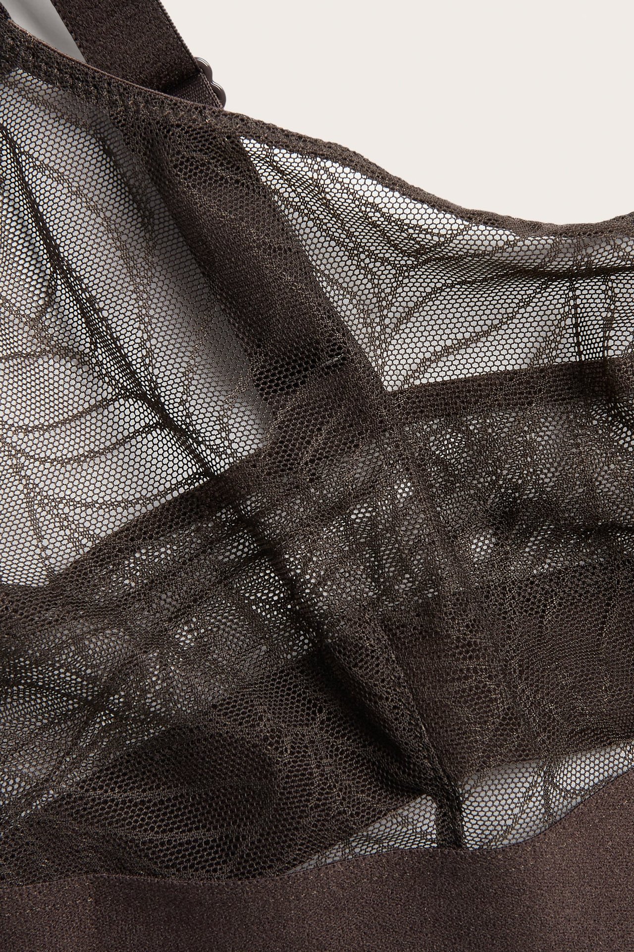 Närbild av en mörkbrun mesh-bralette med ett fint sexkantigt mönster.