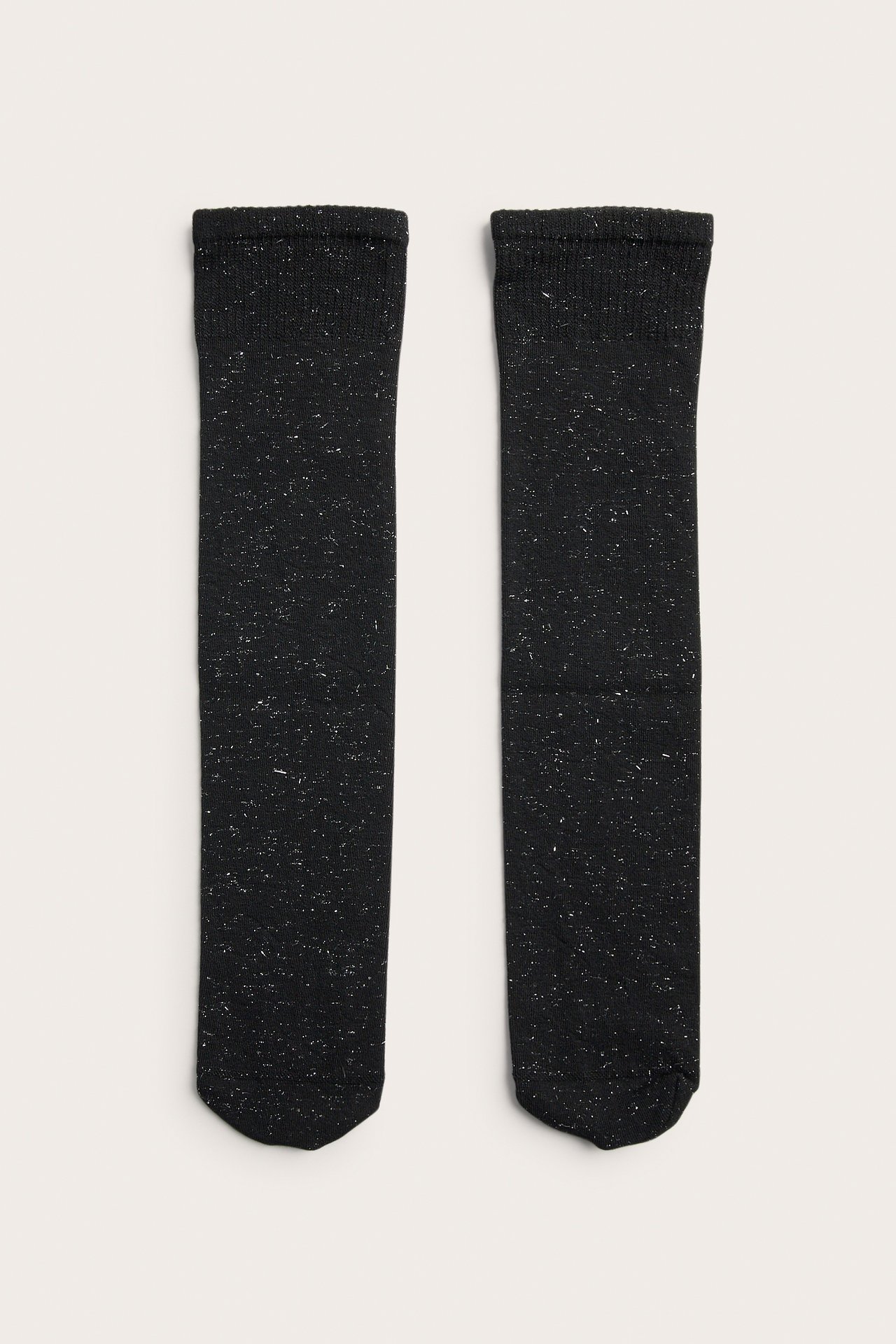 Frontvisning av et par svarte strikkede sokker med hvit glitterdetalj.
