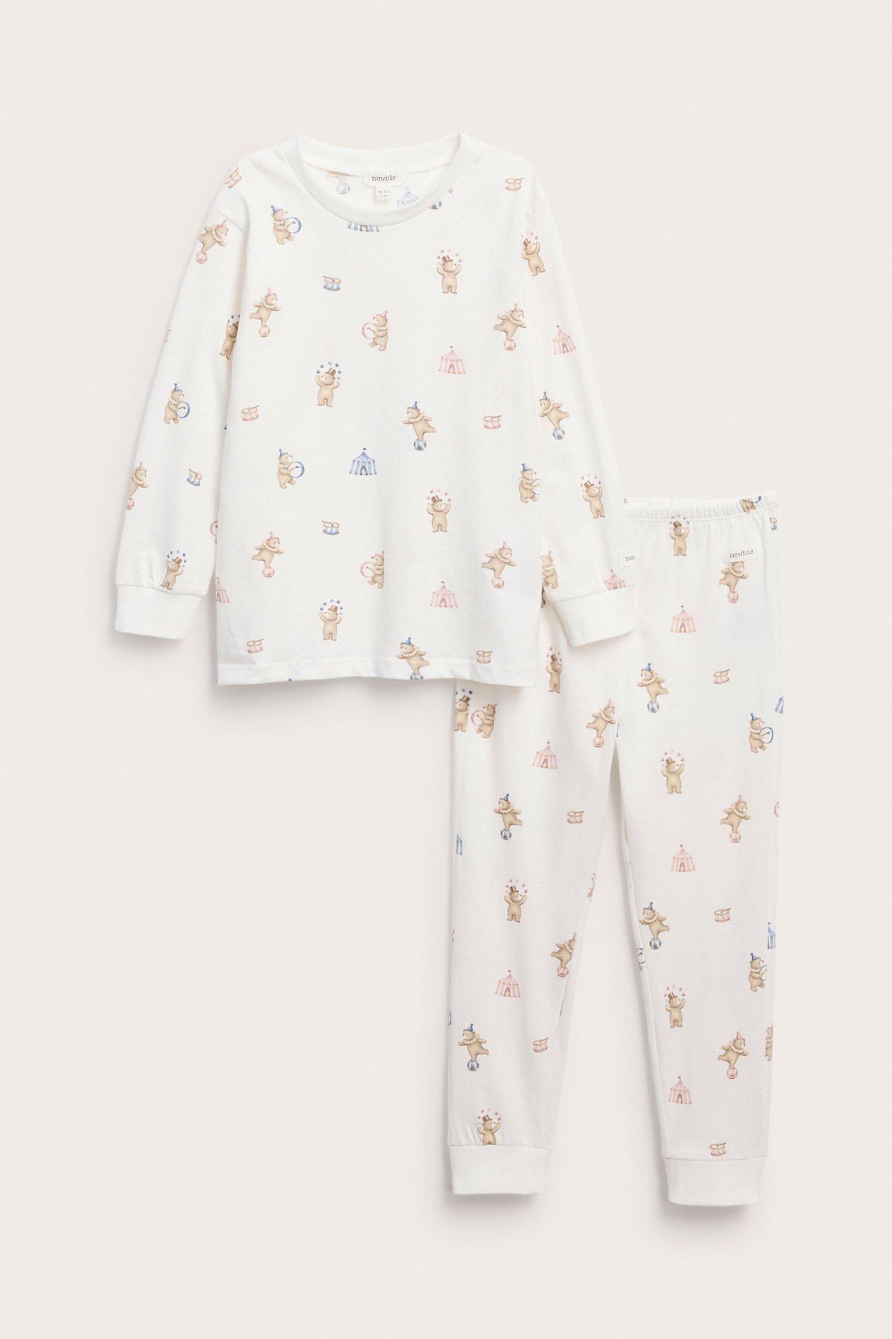 Front av hvit pyjamas for barn med sirkusbjørn og teltmønster.