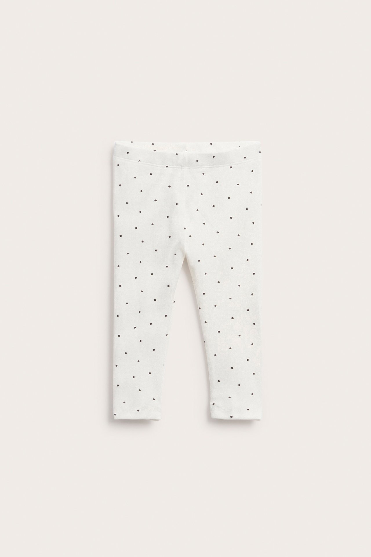 Frontbilde, flatt lagt av hvite baby leggings med svarte prikker.