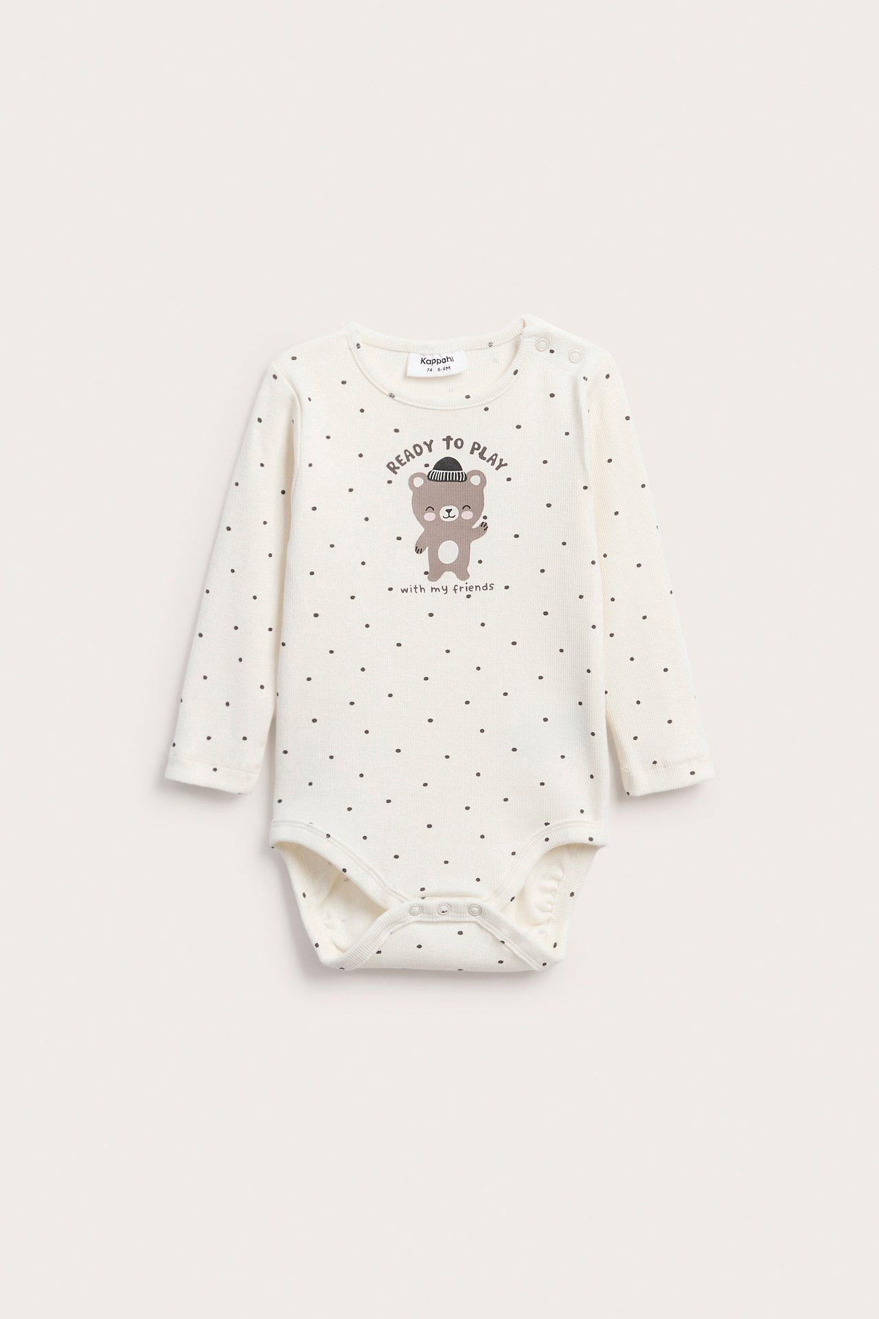 Framsida av en benvit babybody med mörka prickar, med björntryck och tryckknappar.