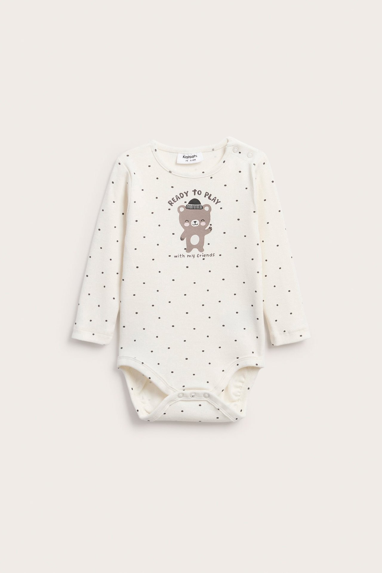 Framsida av en benvit babybody med mörka prickar, med björntryck och tryckknappar.