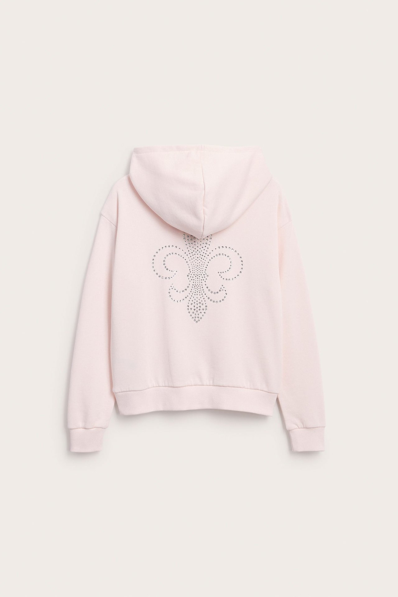Vaaleanpunaisen hupparin takanäkymä hopeisella strassi-fleur-de-lis-kuviolla.