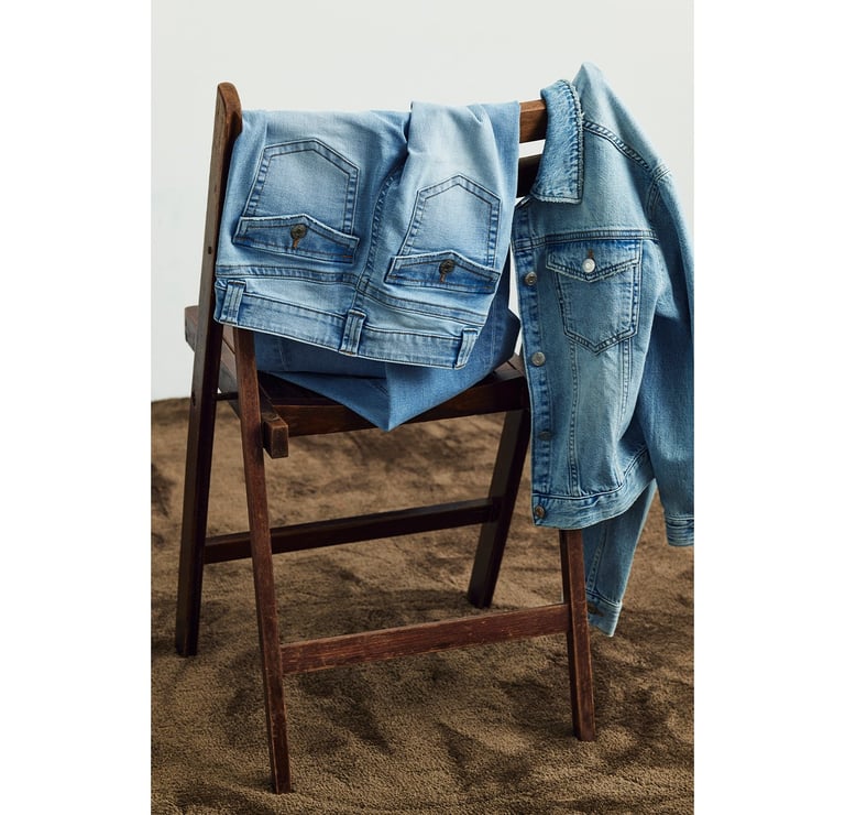 Useita farkkuja roikkumassa tuolilla.